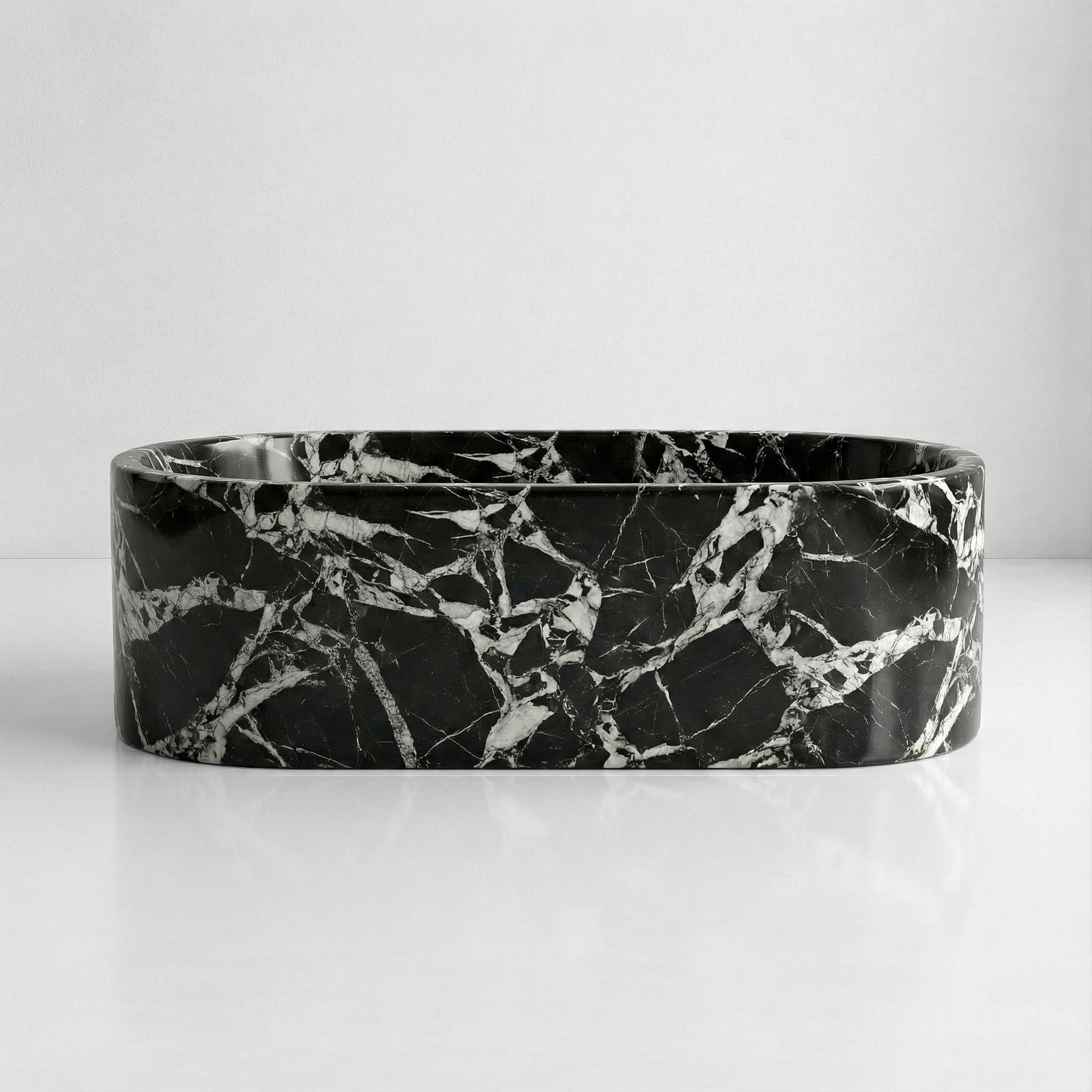 Front elevation of a freestanding Grand Antique marble tub displaying a graphic, monolithic black and white natural stone pattern.