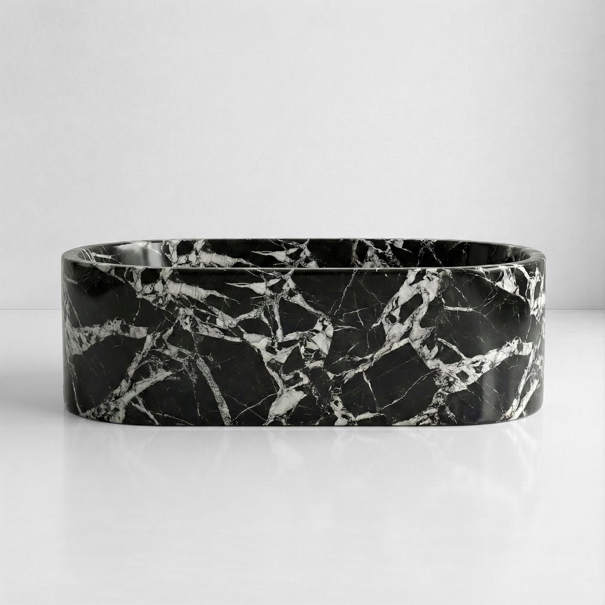 Front elevation of a freestanding Grand Antique marble tub displaying a graphic, monolithic black and white natural stone pattern.