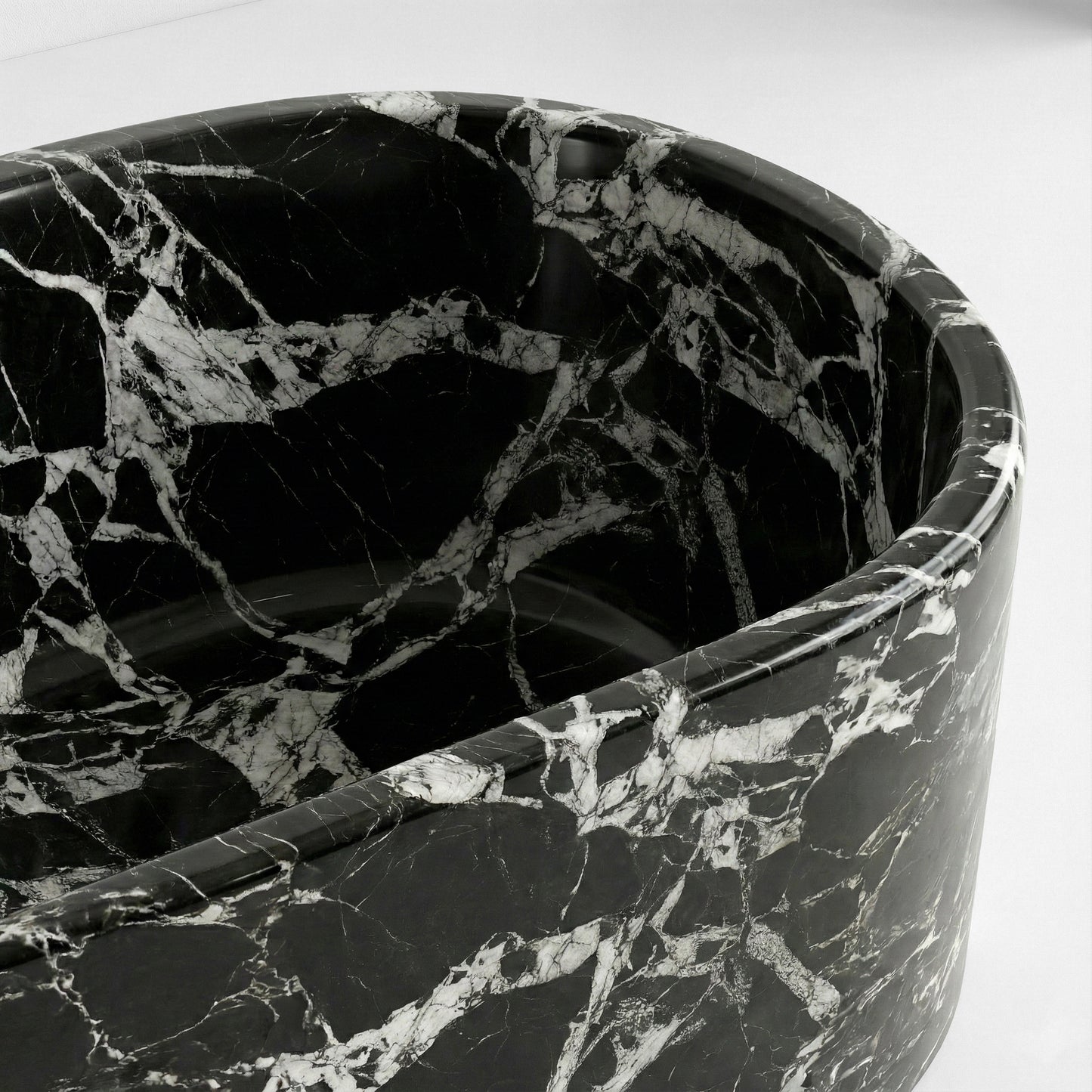 Detail close-up of a Grand Antique marble bathtub rim showing the deep black stone interspersed with dramatic white calcite striations.