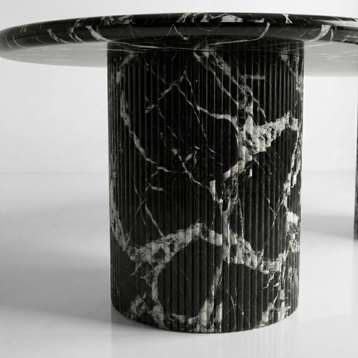 Detail shot of a ribbed column table base made from Grand Antique marble, showcasing the vertical fluting and intense black stone with white inclusions.