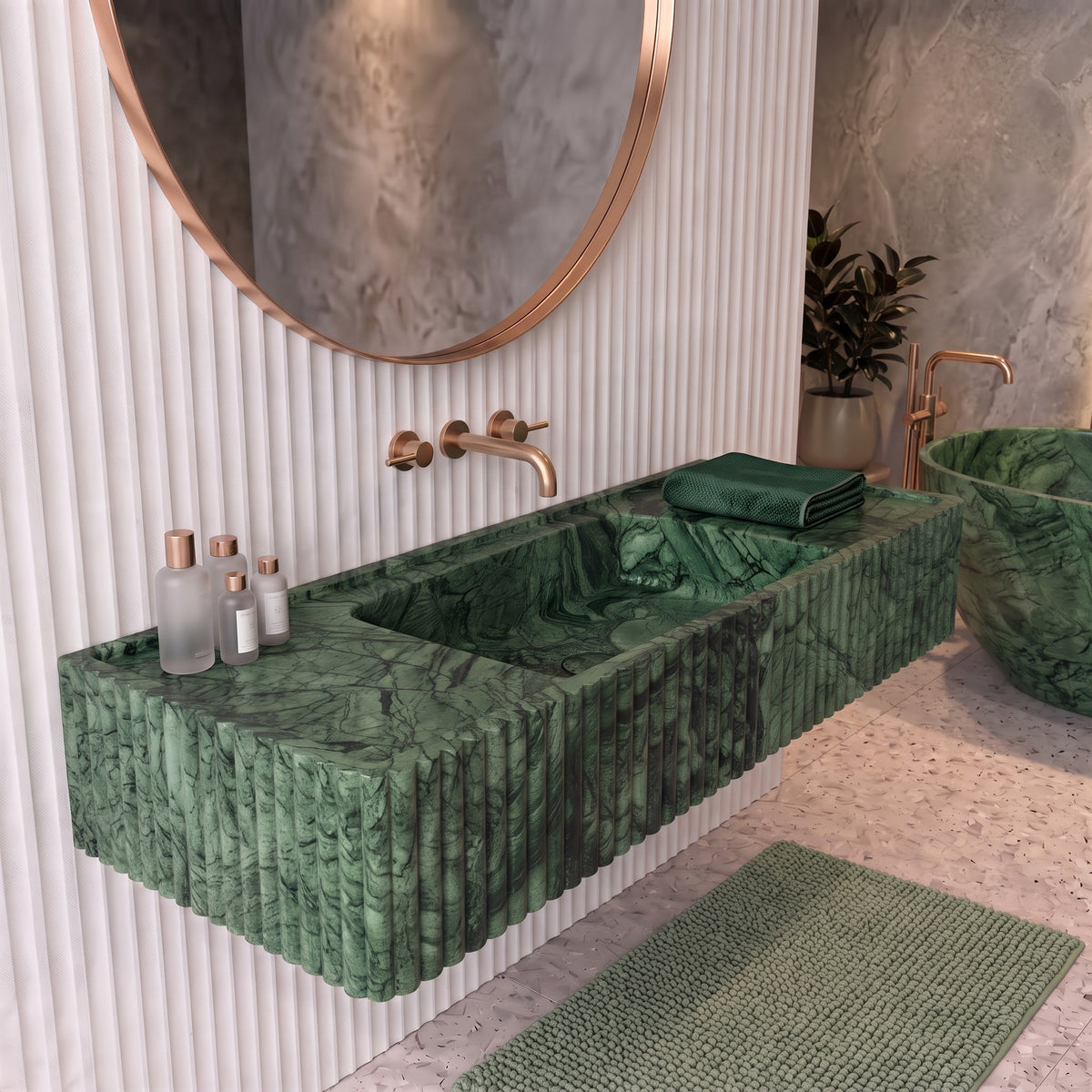 Contemporary spa bathroom interior featuring the floating Green Guatemala fluted stone sink paired with white fluted wall paneling, a rose gold round mirror, and a matching green marble bathtub.