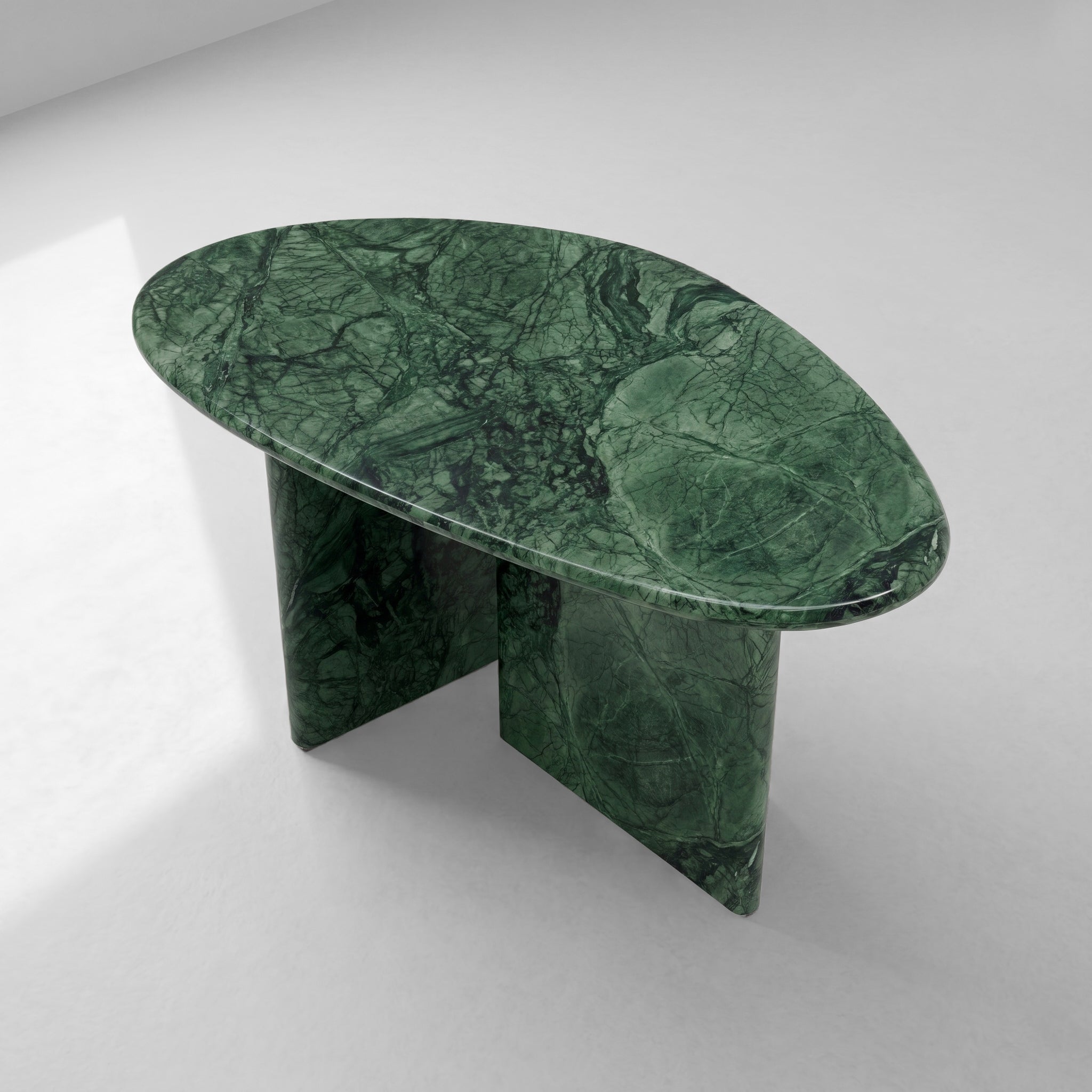Angled top-down view of a Green Guatemala marble coffee table showcasing its organic pebble silhouette and the intricate natural patterns of the polished green stone.