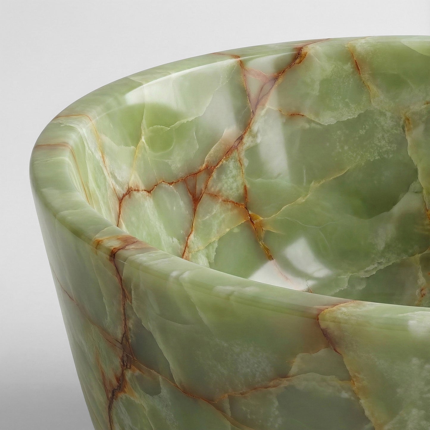 Close-up detail of a Green Onyx bathtub rim highlighting the stone's natural translucency and complex web of jade and brown mineral patterns.