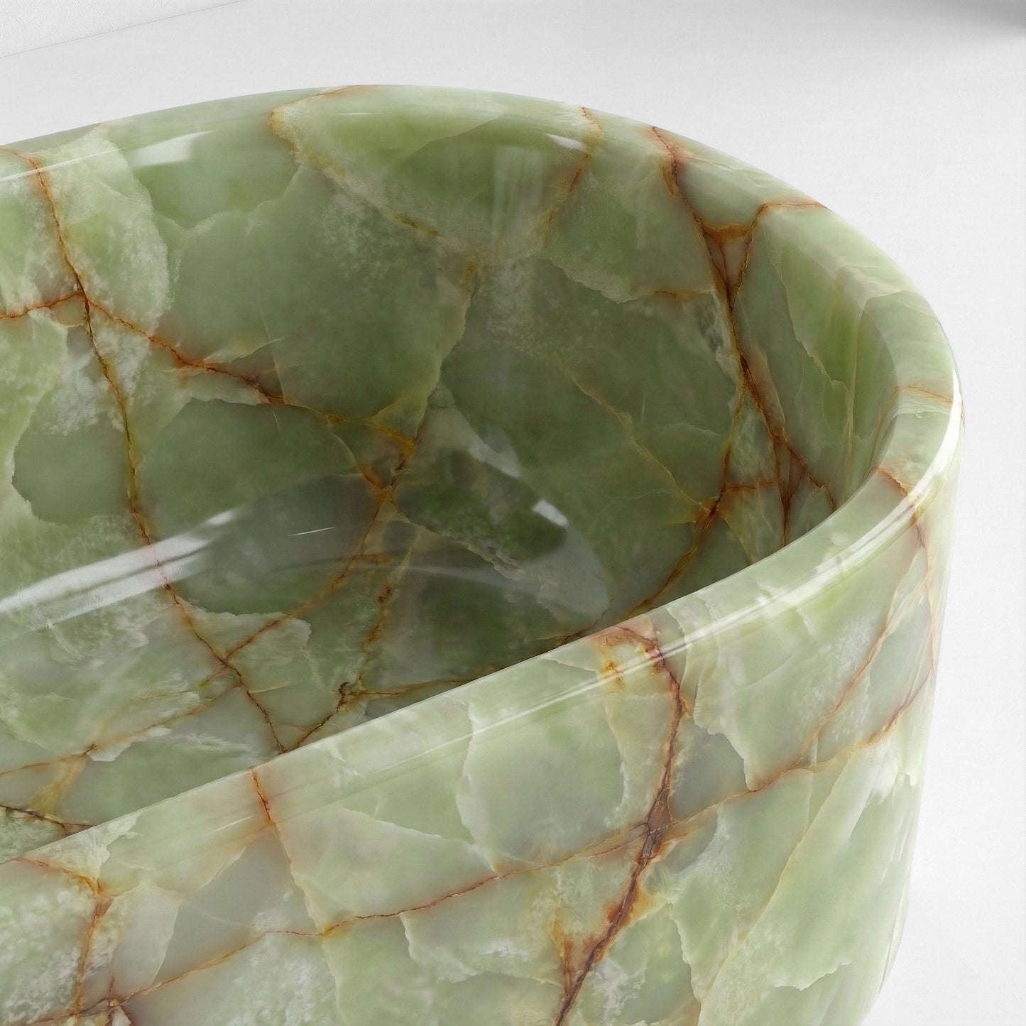 Close-up top view of a Green Onyx bathtub rim highlighting the stone's semi-precious gem quality and intricate natural fracturing patterns.