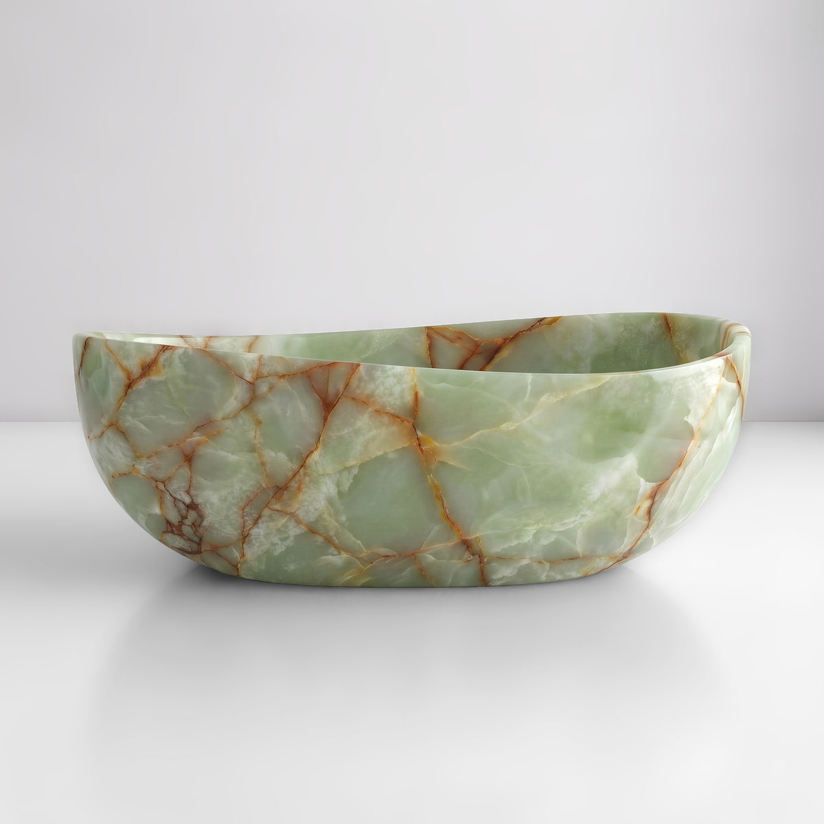 Front studio view of the freestanding Green Onyx wave bathtub, showcasing the organic dipping rim silhouette and luminous jade-green crystalline field with warm amber-rust veining across the polished stone exterior.