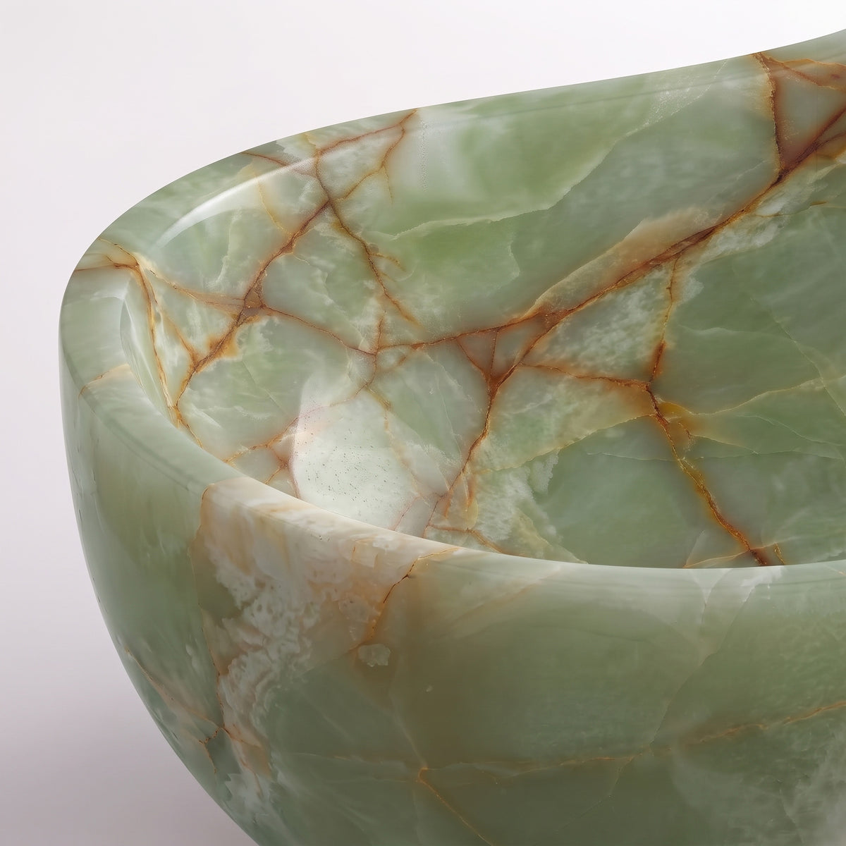 Close-up overhead detail shot of the Green Onyx wave bathtub rim, displaying the hand-finished curve, polished stone translucency, and warm honey-amber crystalline fractures running through pale mint onyx.