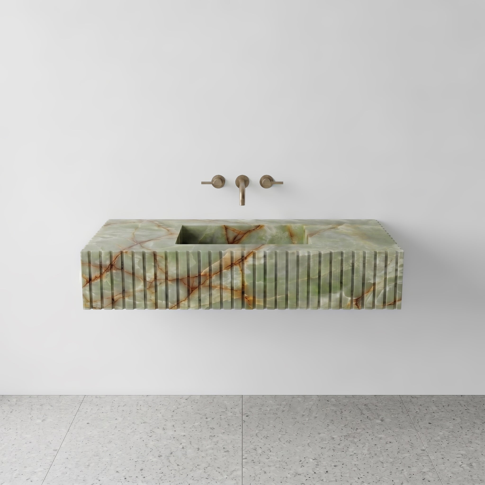 Front studio view of a luxury floating single washbasin vanity crafted from translucent Green Onyx, featuring a precision-cut fluted apron front design and a wall-mounted brushed bronze faucet.