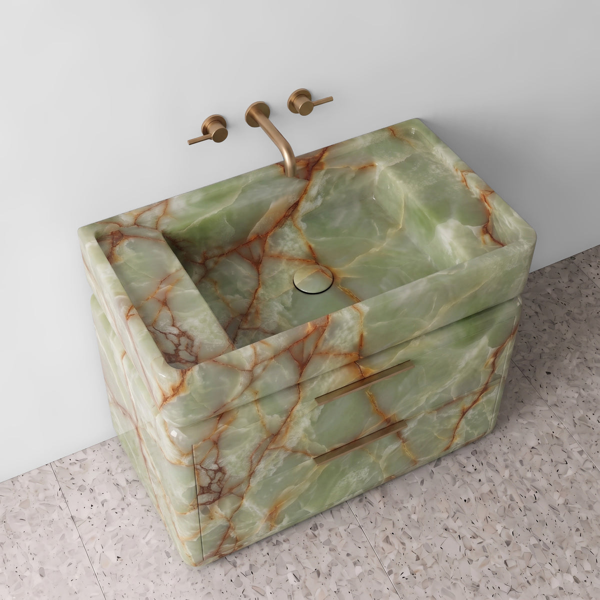 High-angle perspective view of the Green Onyx double-drawer vanity, highlighting the integrated trough sink with a matching stone drain cover, raised perimeter border, rounded drawer corners, brushed brass linear pulls, and translucent jade-green stone fractured by amber veining.