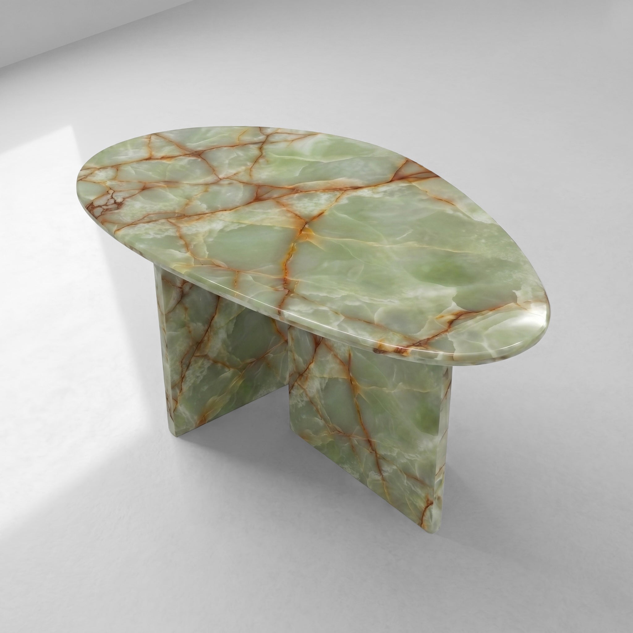 High-angle top view of a pebble-shaped coffee table crafted from premium green onyx, emphasizing the unique organic silhouette and natural beauty of the stone's patterns.