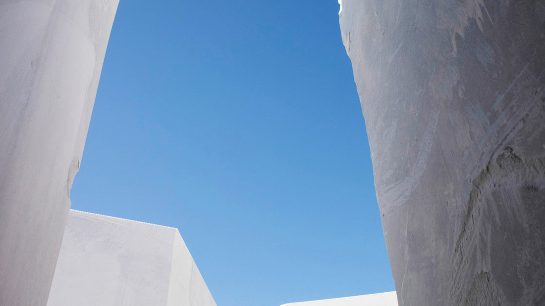 Massive raw white marble blocks in a quarry under a clear sky. GustavDesign premium sourcing for bespoke marble bathtubs, marble sinks, and custom marble furniture.