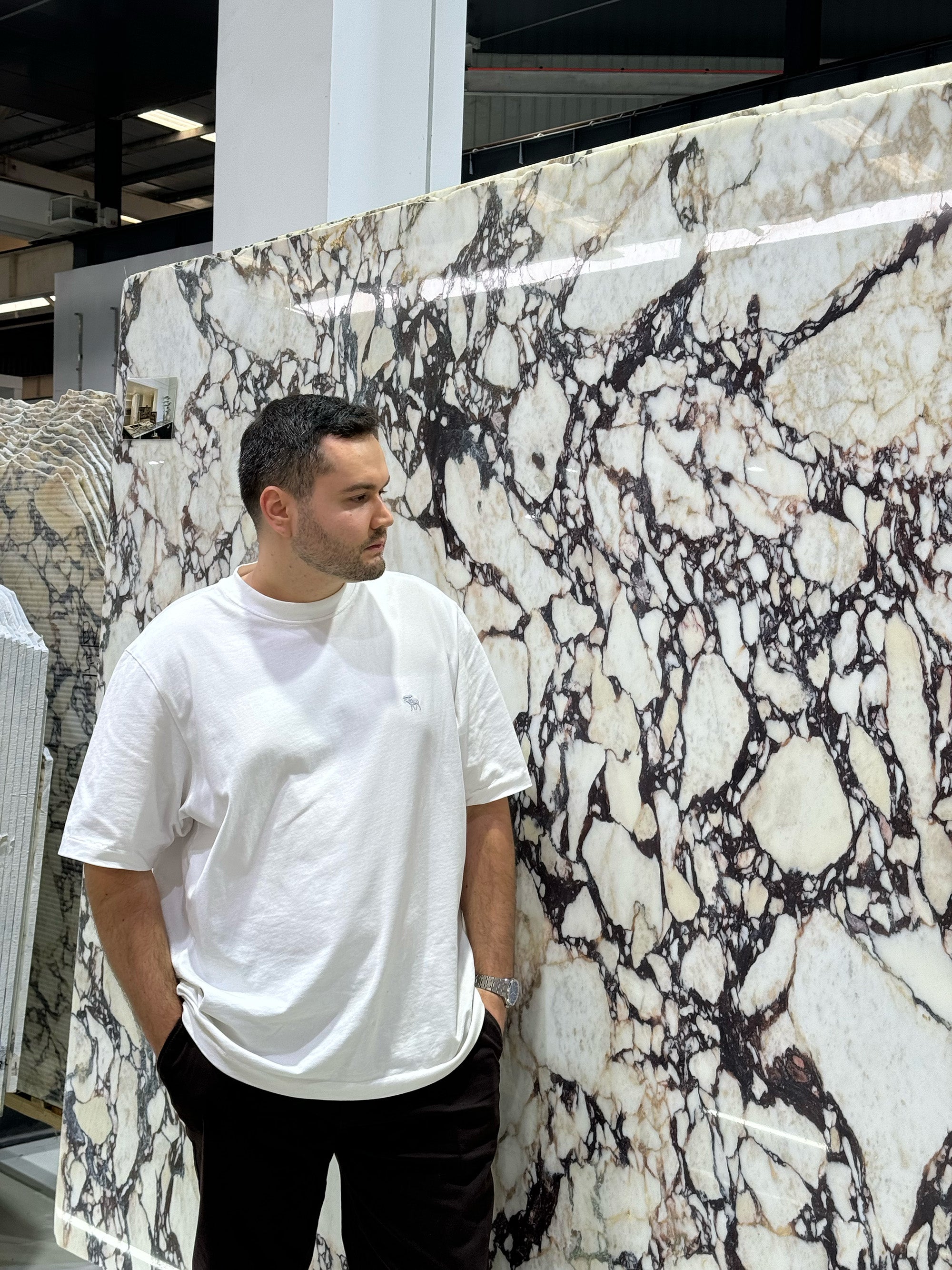 A large-scale Calacatta Viola marble slab displayed at a stone gallery, illustrating the dramatic patterns available for GustavDesign bespoke dining tables.