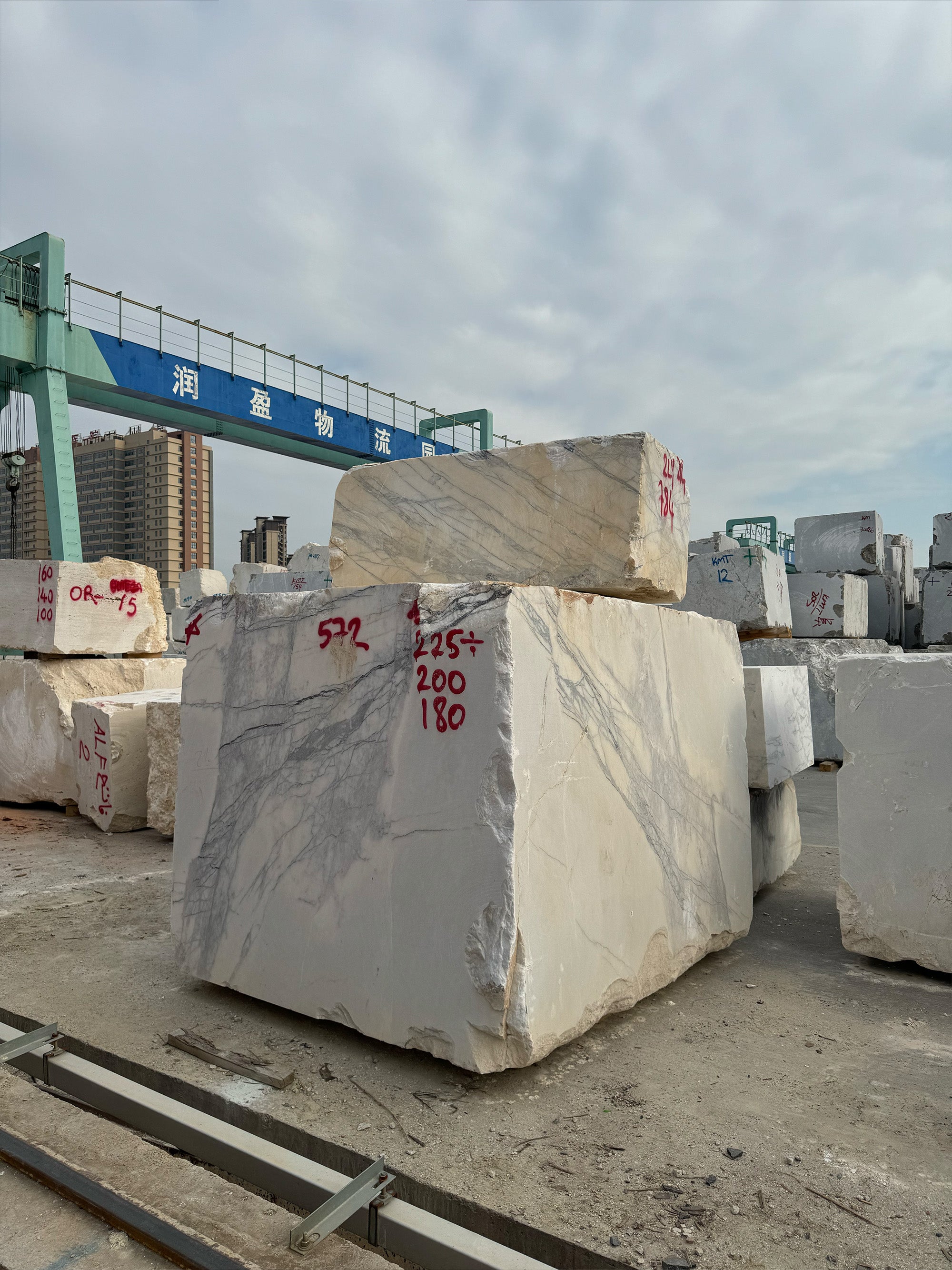 Large Italian marble blocks at a global logistics hub, ready for export and precision cutting into custom marble slabs for GustavDesign clients.