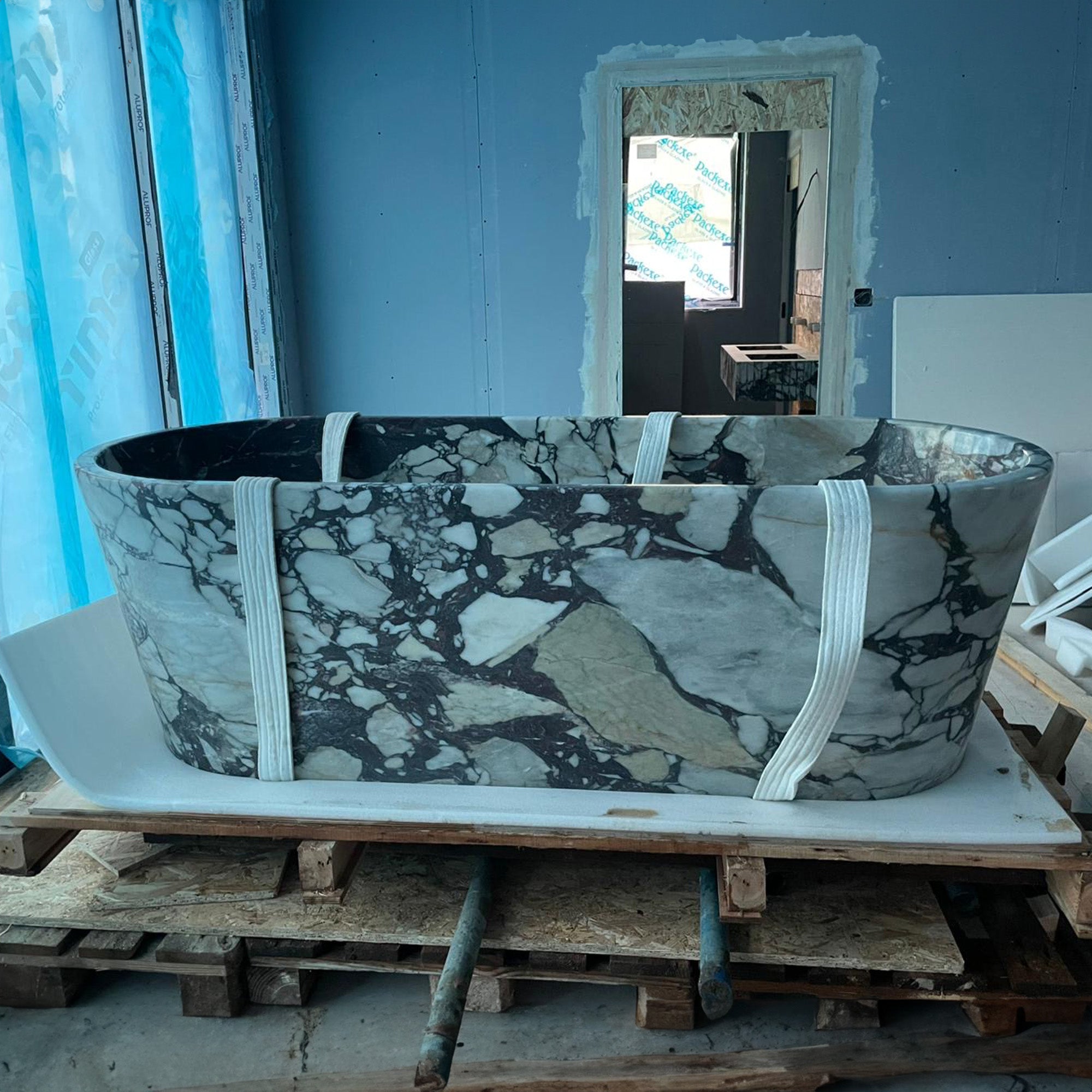 A magnificent bespoke Calacatta Viola marble bathtub secured on a shipping pallet with heavy-duty straps, highlighting GustavDesign’s expertise in the international delivery and installation of large-scale luxury stone commissions.