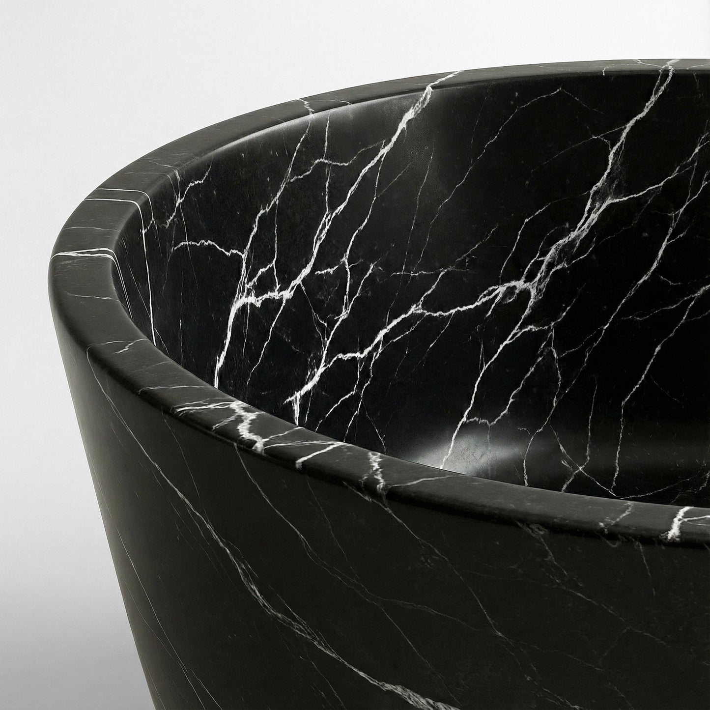 Close-up detail of a Nero Marquina bathtub rim showing the high-contrast natural stone pattern of sharp white lightning veins on a black background.