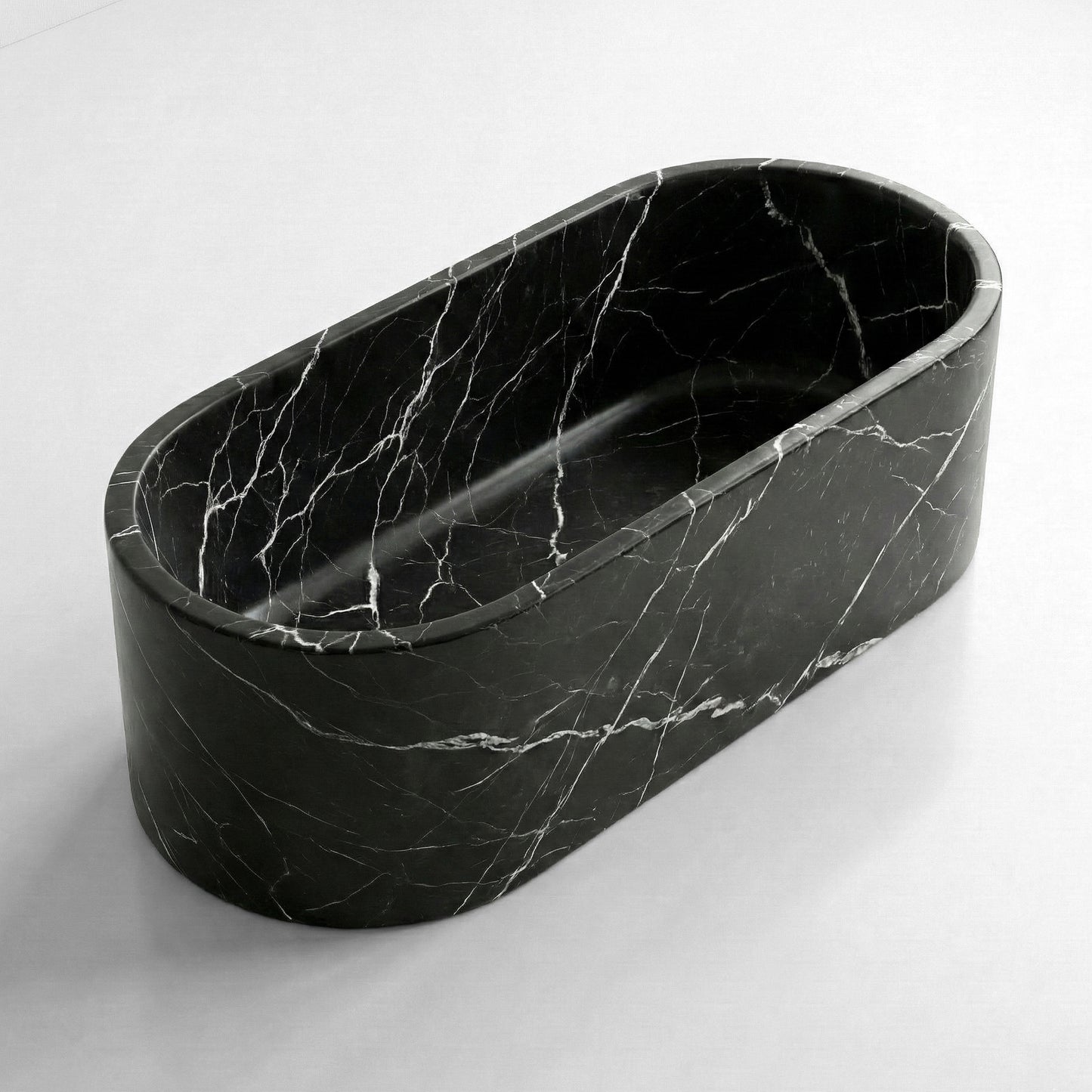 Isometric side view of a solid Nero Marquina stone tub, emphasizing the seamless honed finish and dramatic diagonal veining.