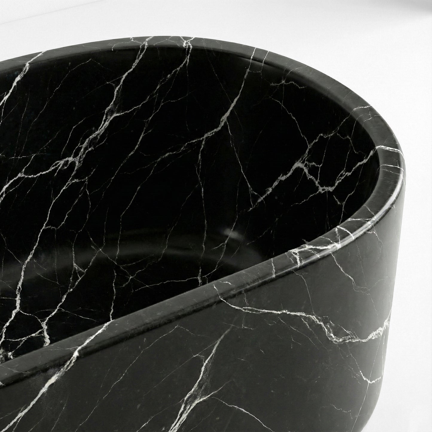 Close-up detail of a Nero Marquina bathtub rim showing the deep black polished surface interrupted by striking white lightning veins.