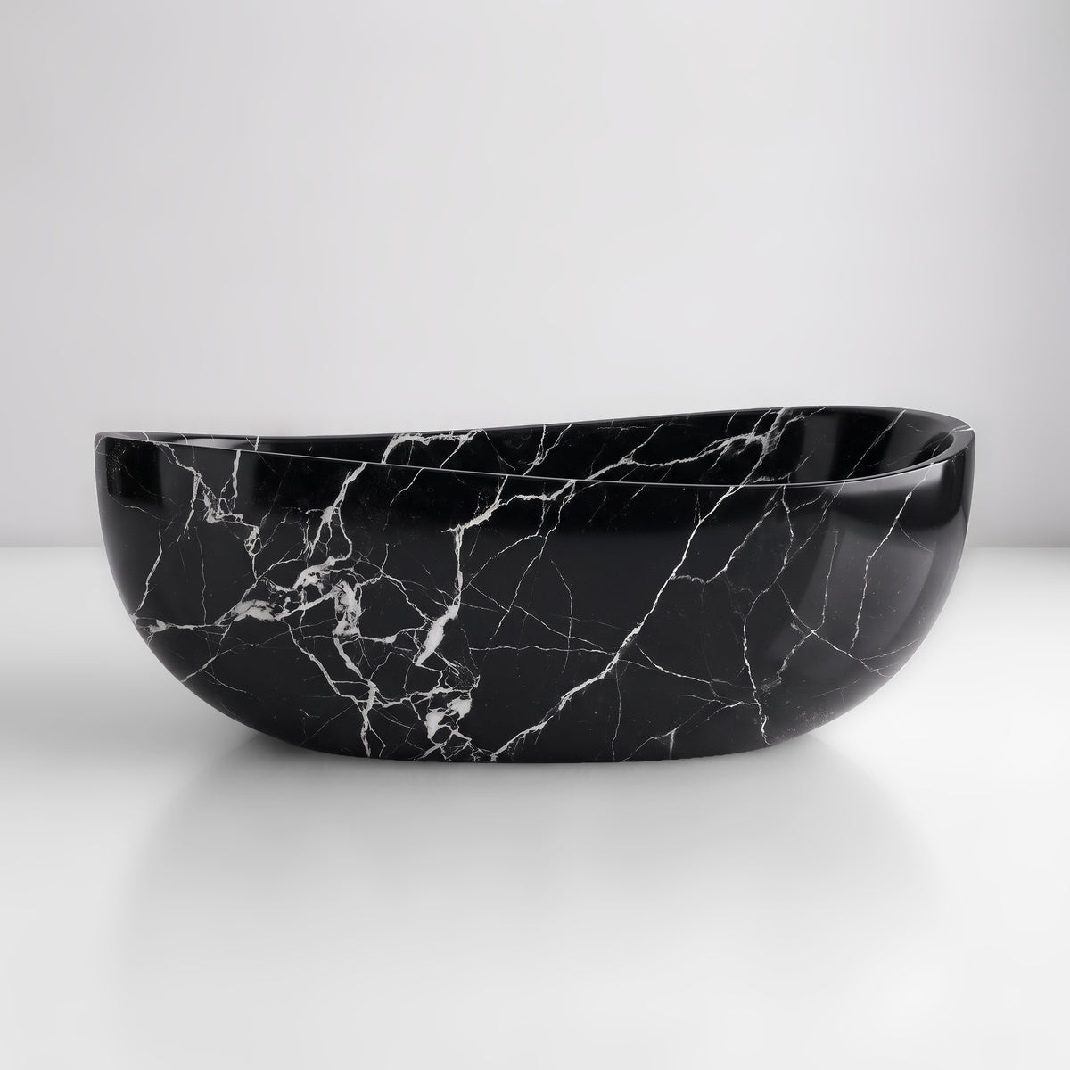 Front studio view of the freestanding Nero Marquina marble wave bathtub, showcasing the organic dipping rim silhouette and crisp white calcite veining across the deep black polished stone exterior.