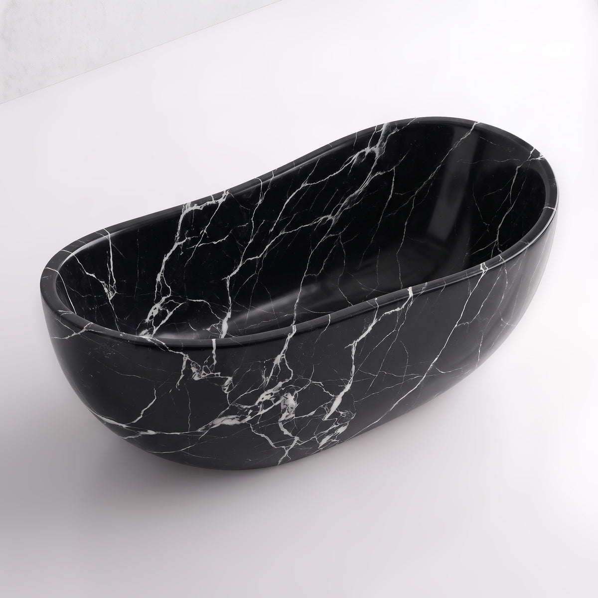 Elevated three-quarter perspective view of the Nero Marquina marble wave soaking tub, highlighting the asymmetrical undulating rim, seamless solid-carved interior, and striking white spiderweb veining across obsidian-black stone.