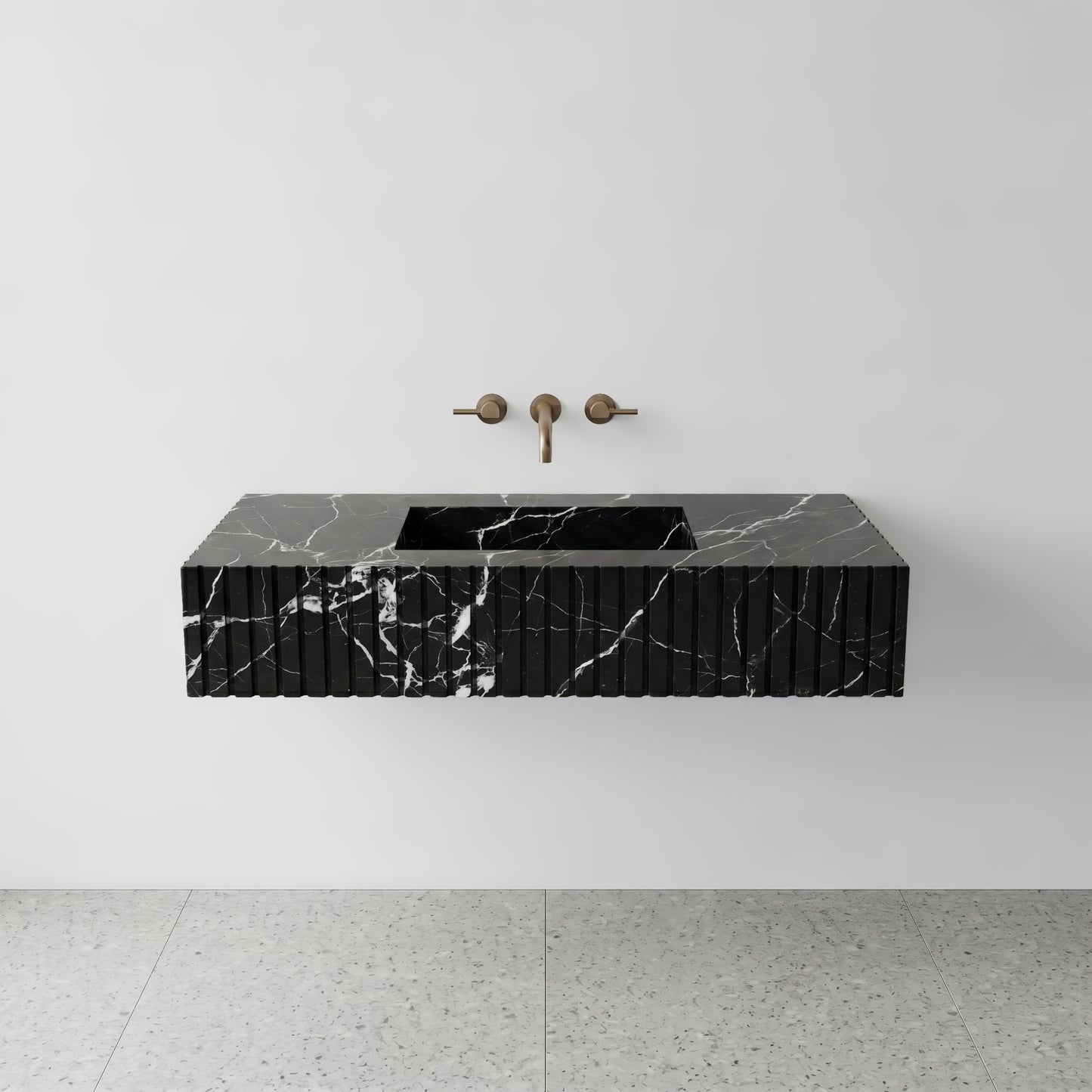Front studio view of a luxury floating single washbasin carved from Nero Marquina black marble, showcasing a geometric fluted apron front design and a wall-mounted brushed bronze faucet.