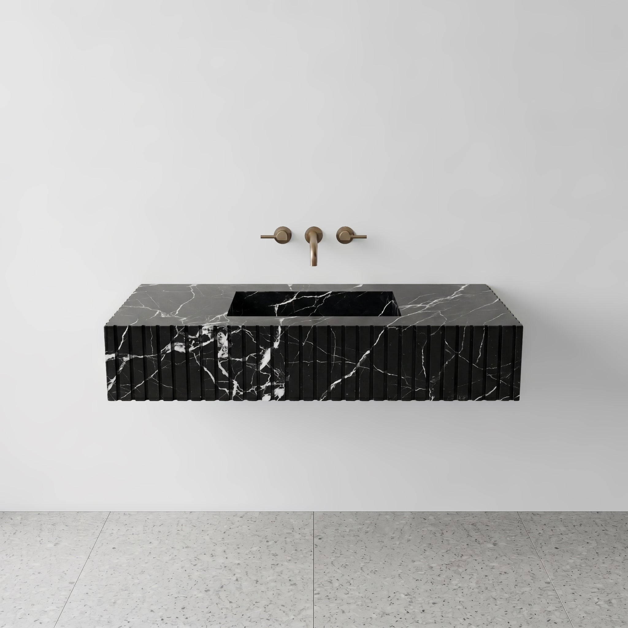 Front studio view of a luxury floating single washbasin carved from Nero Marquina black marble, showcasing a geometric fluted apron front design and a wall-mounted brushed bronze faucet.
