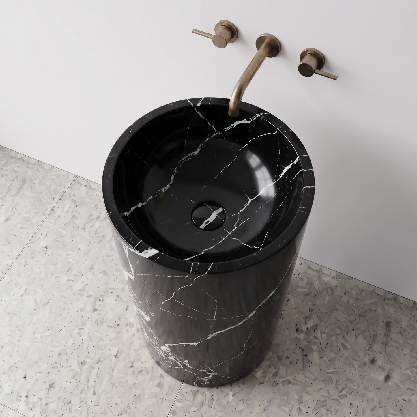High-angle top view of a Nero Marquina cylindrical black marble pedestal sink highlighting bold white lightning veining and matching carved stone drain cover.