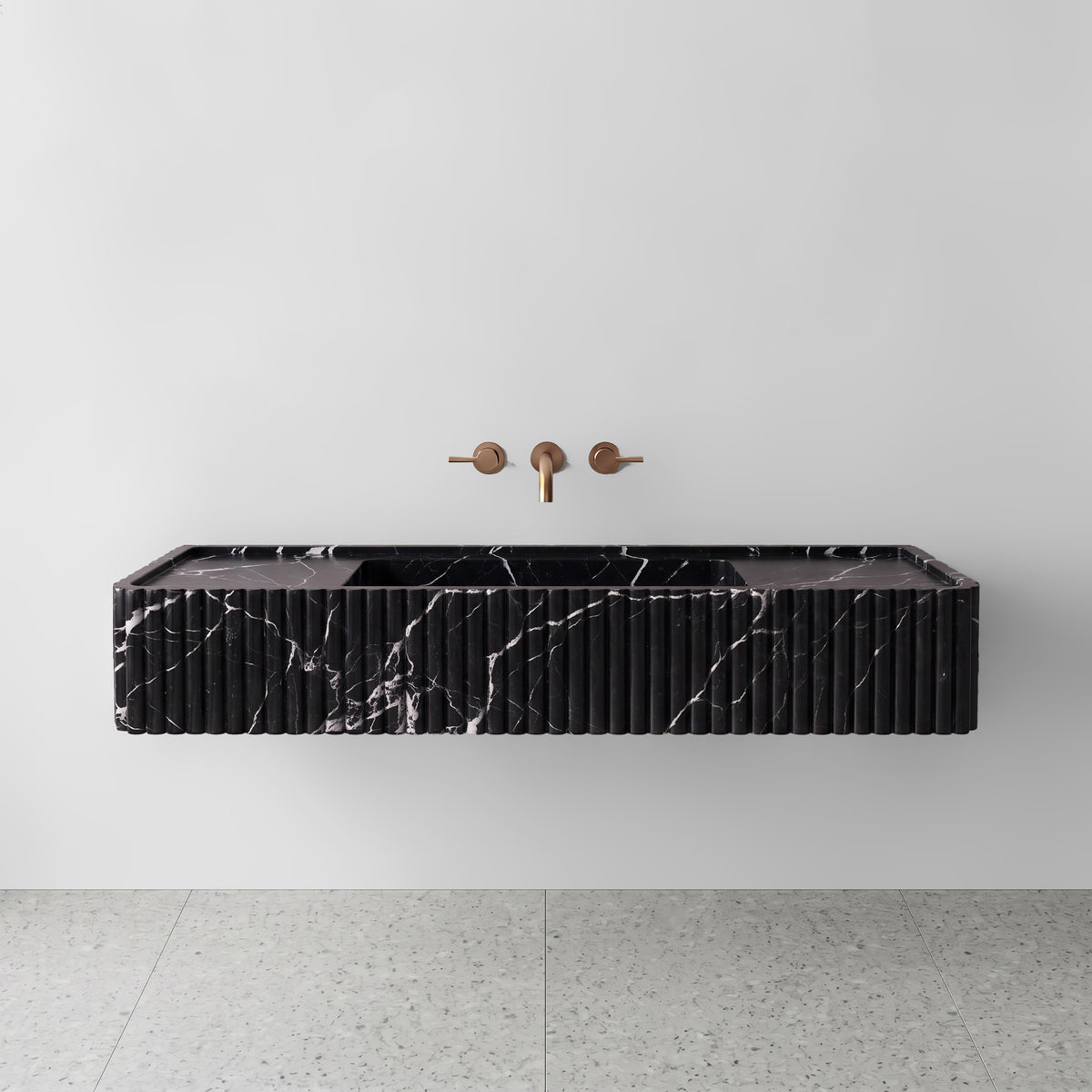 Front view of the Nero Marquina marble fluted monolith sink showing crisp white calcite veining across the vertical convex ribbed apron and wall-mounted brushed bronze faucet.