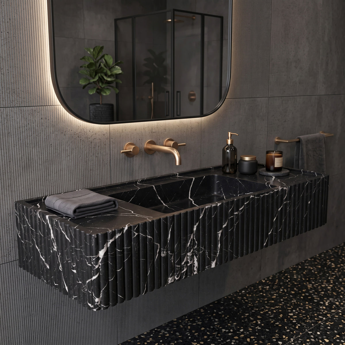 Moody contemporary bathroom interior featuring the floating Nero Marquina fluted stone sink paired with dark ribbed wall cladding, a backlit pill mirror, and dark terrazzo flooring.