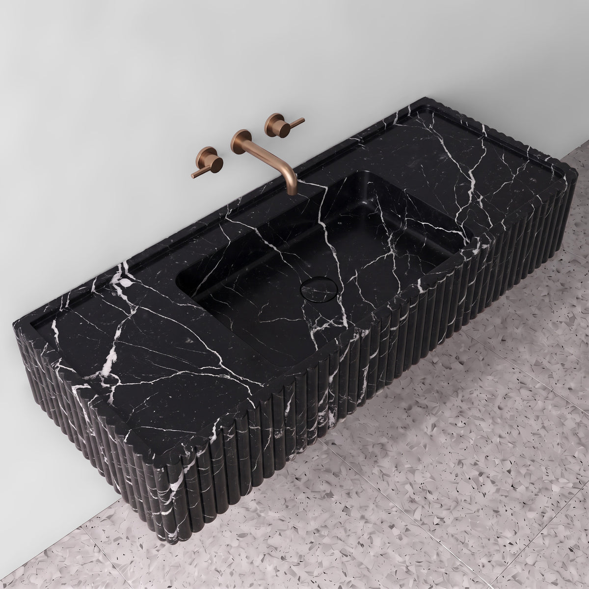 Elevated three-quarter angle of the Nero Marquina fluted monolith sink showing the integrated trough basin, matching stone drain cover, raised perimeter edge, and ribbed side detailing.
