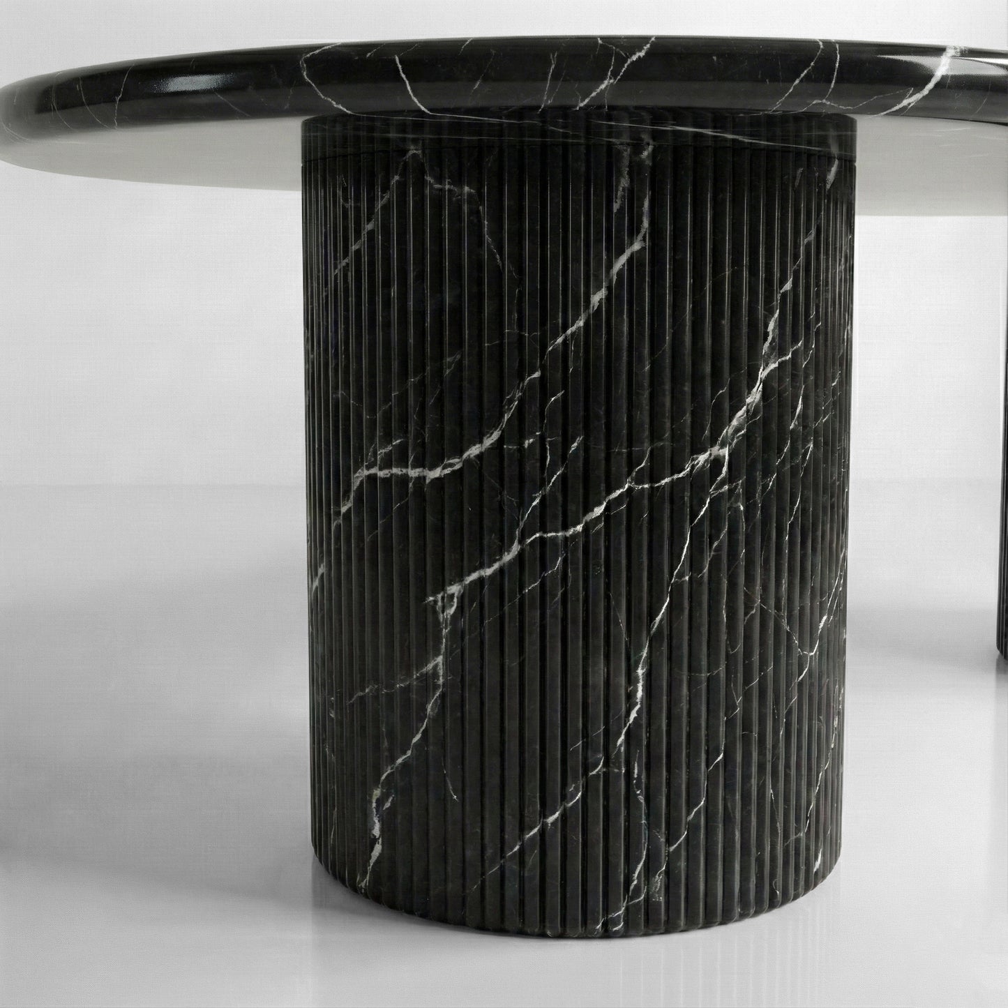 Detail shot of a fluted column table base crafted from Nero Marquina marble, highlighting the vertical ribbed texture and intense black stone finish.