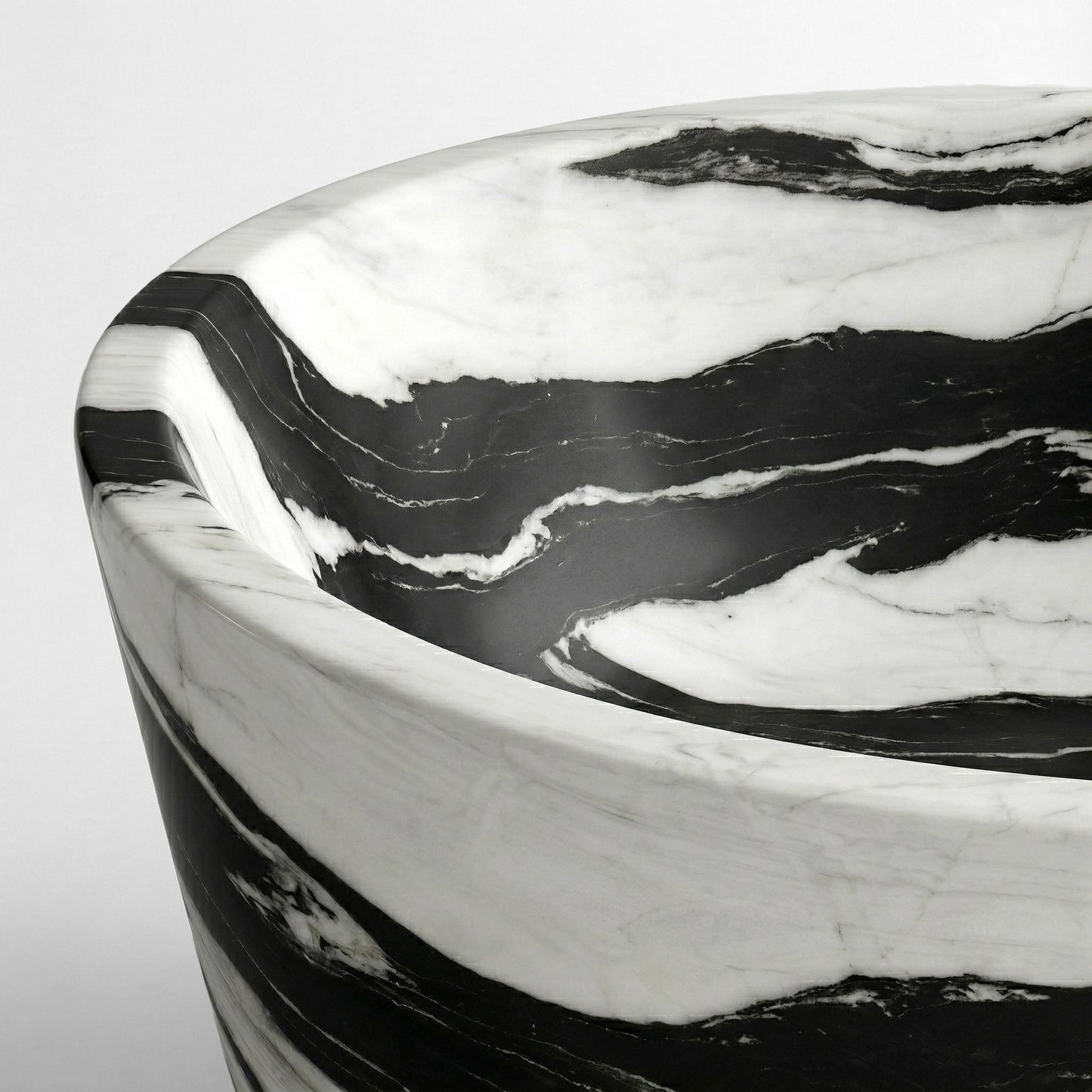 Close-up detail of a Panda White bathtub rim highlighting the fluid transition between ink-black veins and bright white marble.