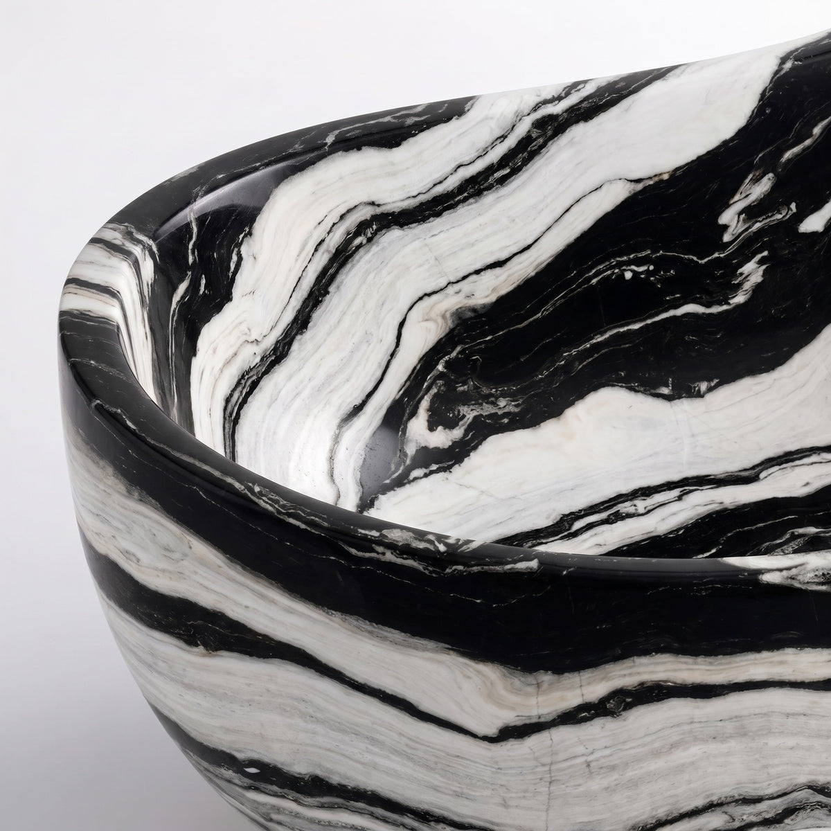 Close-up overhead detail shot of the Panda White marble wave bathtub rim, displaying the hand-finished curve, polished stone texture, and fluid, ink-like black-and-white veining pattern along the interior and exterior surfaces.