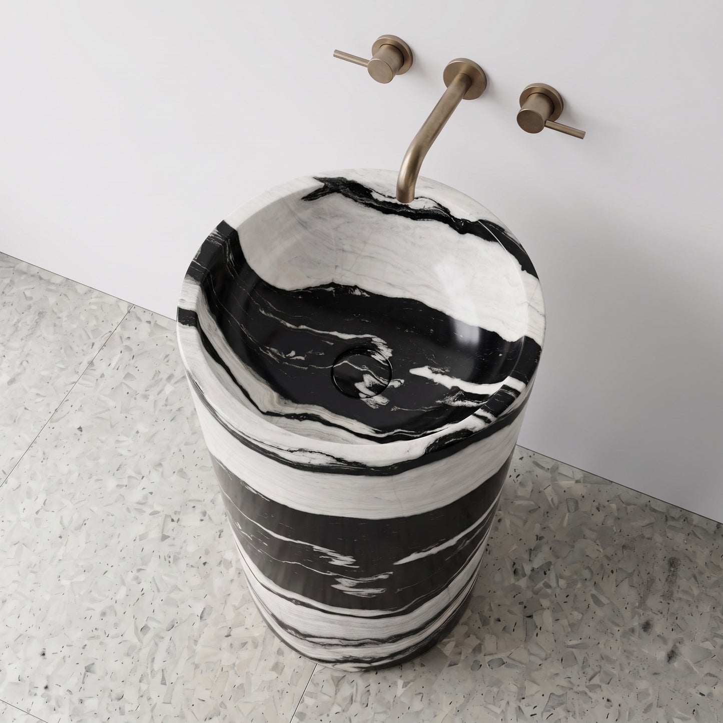 High-angle top view of a Panda White cylindrical marble pedestal sink highlighting expressive ink-wash style veining and matching integrated carved stone drain cap.