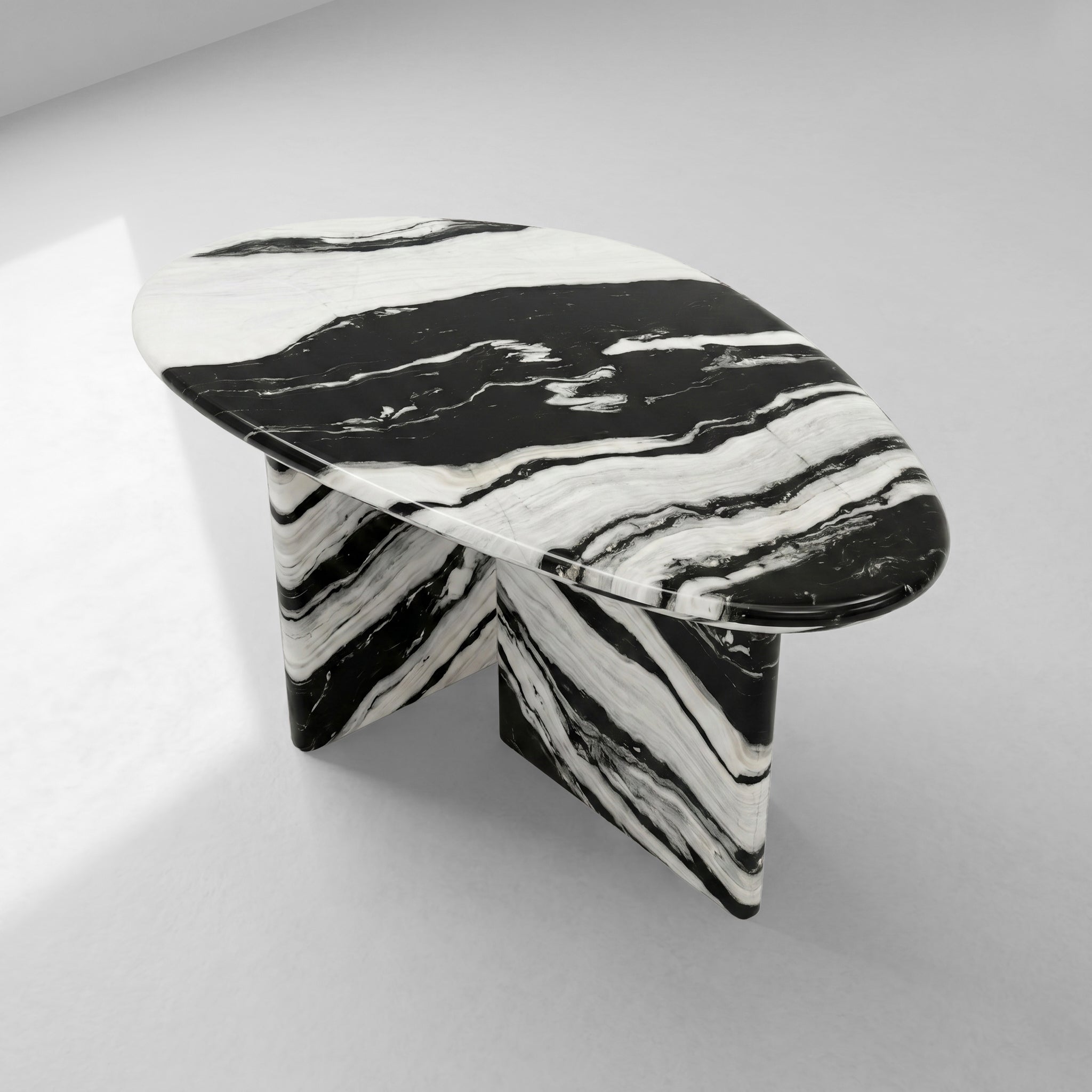 High-angle view of a contemporary pebble-shaped coffee table crafted from Panda White marble, emphasizing its unique organic silhouette and striking natural stone artistry.
