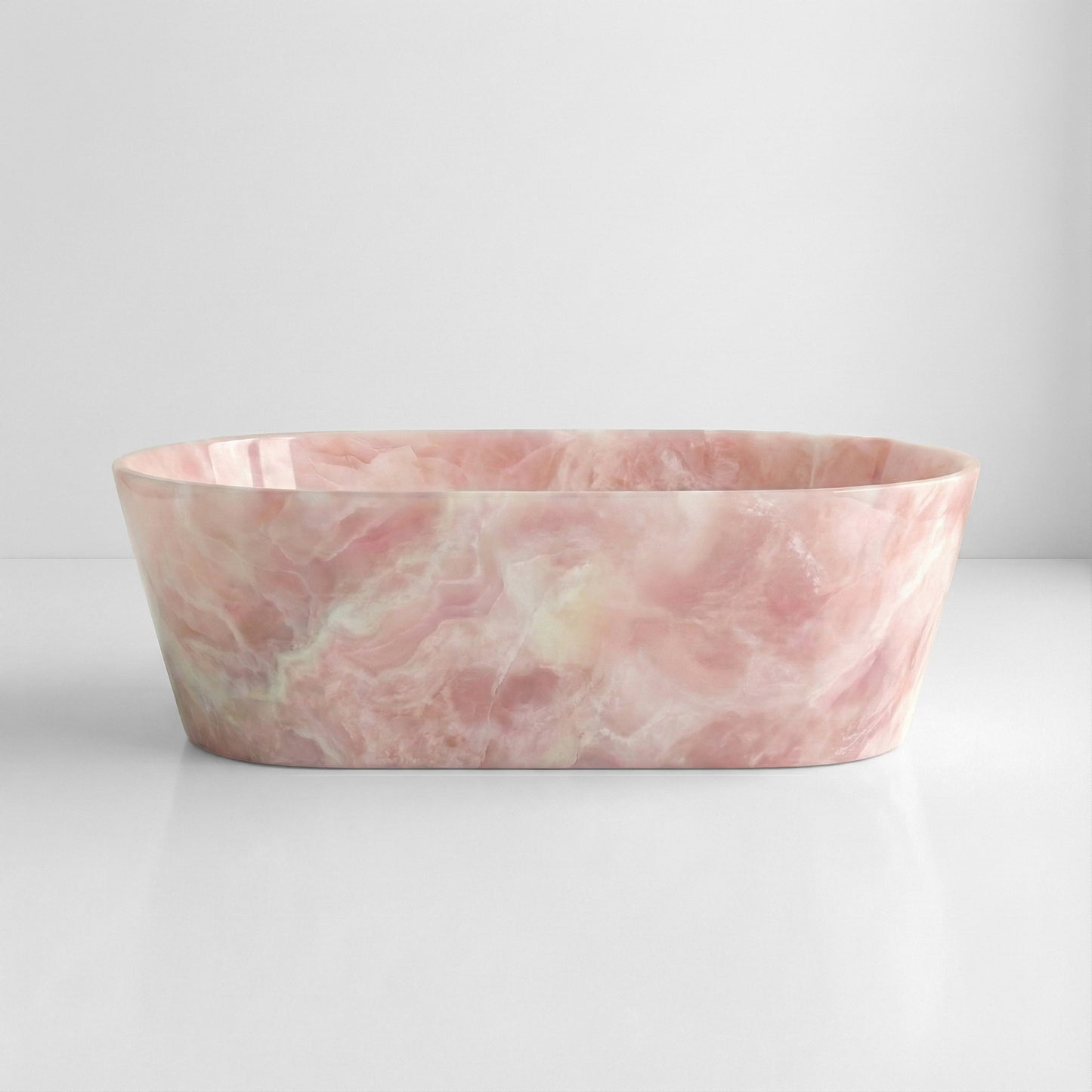 Front profile of a statement Pink Onyx gemstone bathtub, displaying soft rose quartz tones and a natural translucent stone finish.