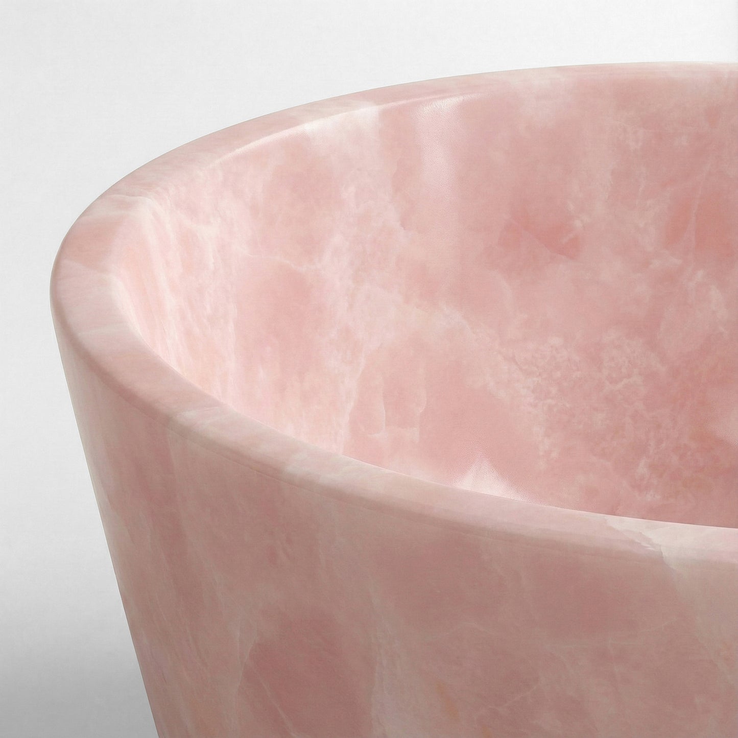 Close-up detail of a Pink Onyx bathtub rim showing the semi-precious stone's crystalline structure and cloudy white-and-pink veining.