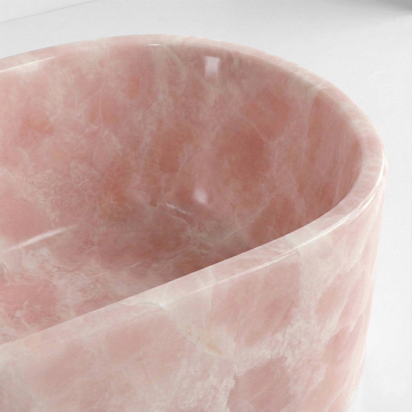 Close-up detail of a Pink Onyx bathtub rim featuring a soft rose color palette and cloud-like white crystalline patterns.