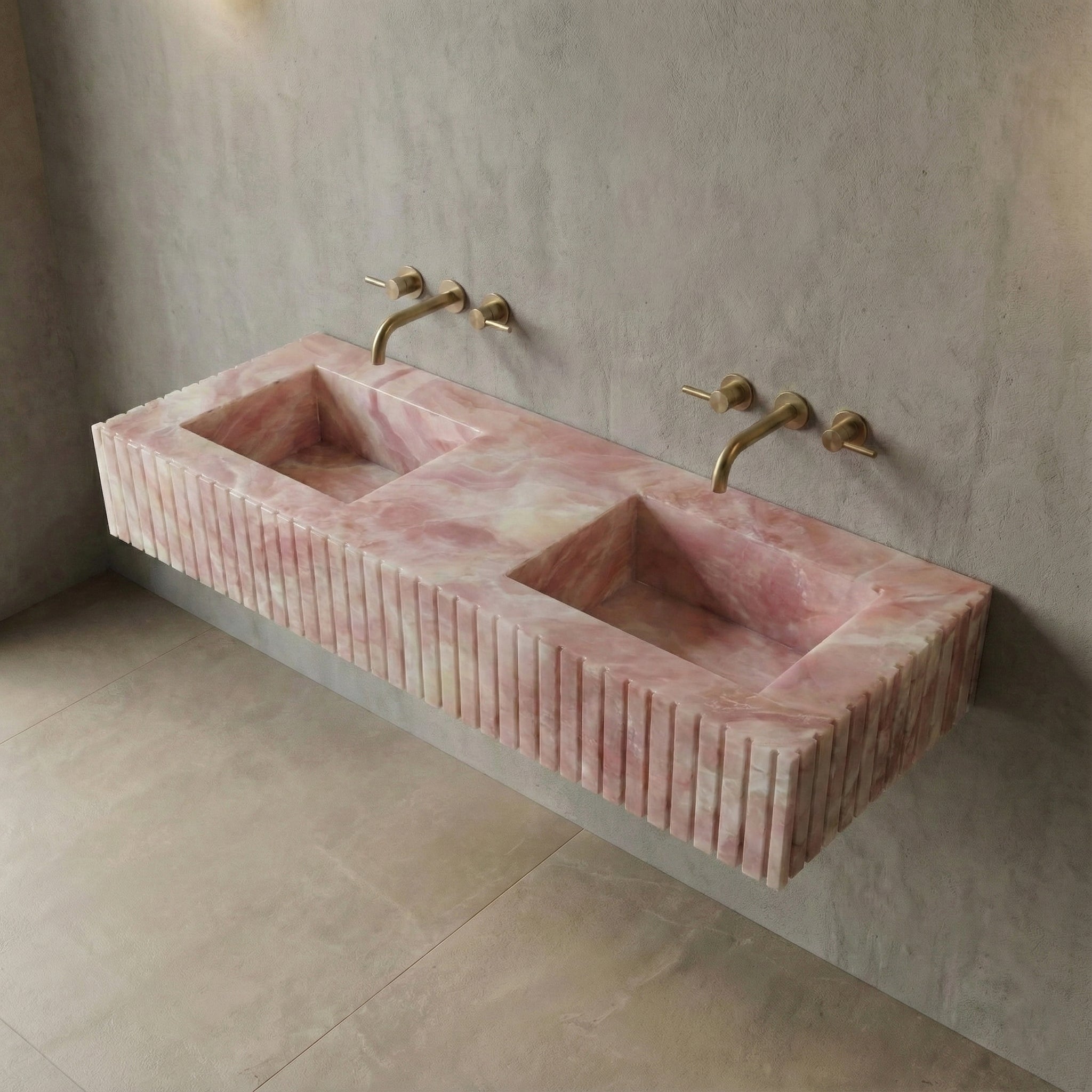 High-angle view of a wall-mounted Pink Onyx gemstone sink featuring dual integrated basins and a custom fluted stone apron.