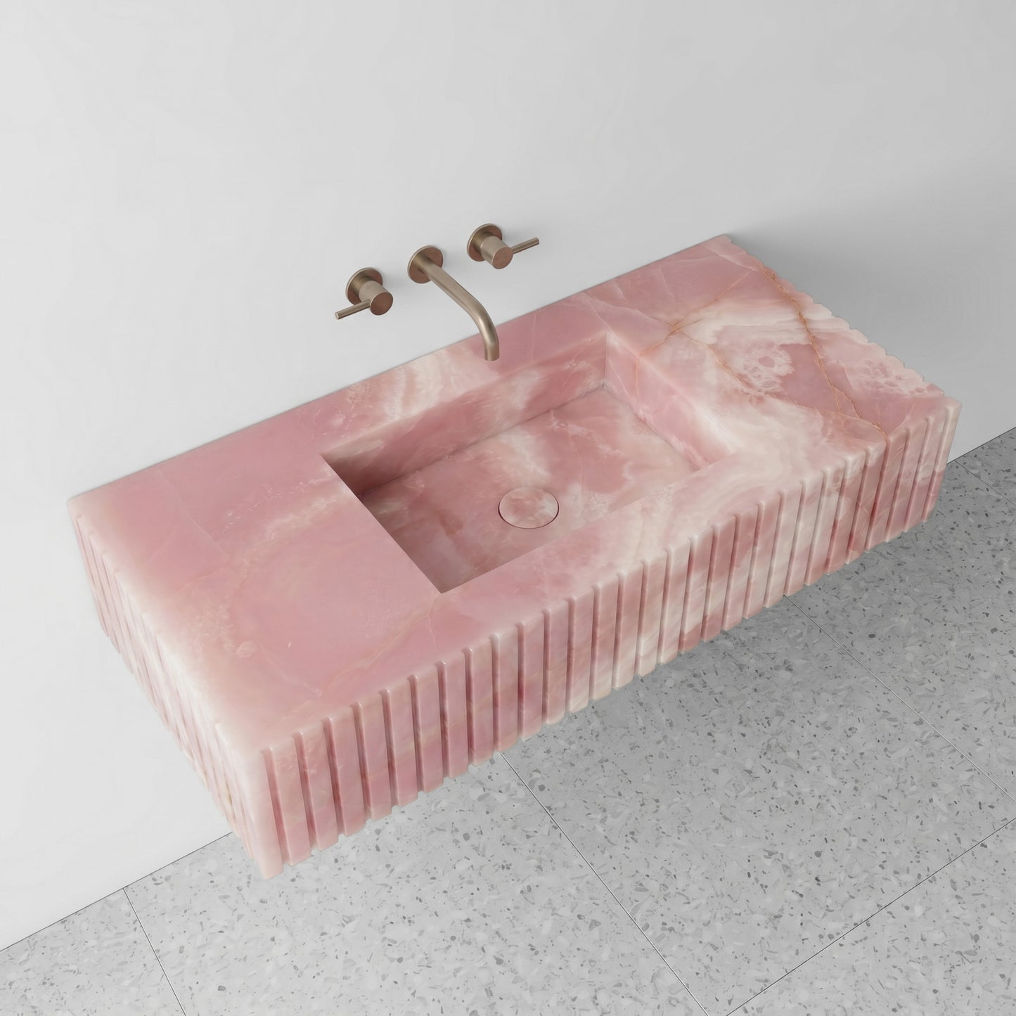 High-angle perspective view of a floating Pink Onyx single vanity, showcasing the crystalline pooling, an integrated square sink with a matching stone drain cover, and terrazzo floor tiles.
