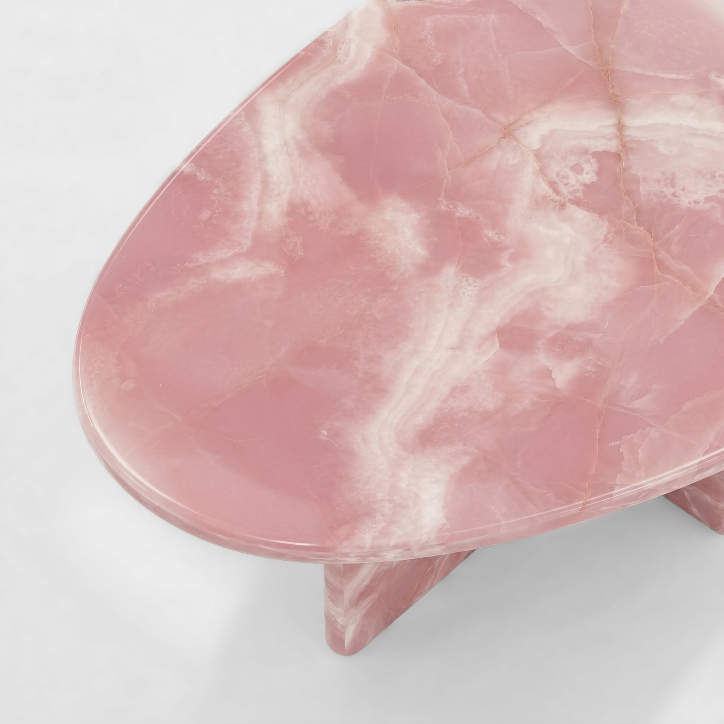 Side profile of a luxury pink onyx coffee table featuring a sculptural two-pedestal base and an organic pebble-shaped top against a minimalist white background.