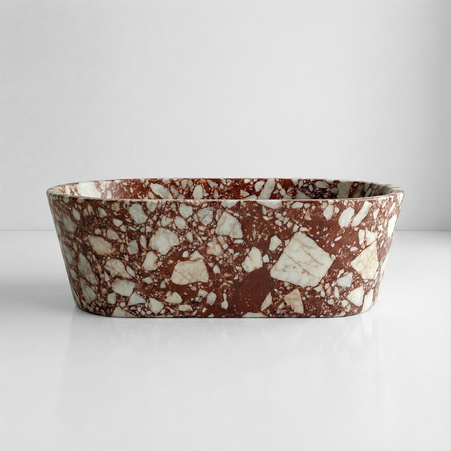 Front profile view of a luxury Red Bulgari marble bathtub displaying a dramatic, high-contrast mosaic pattern of white marble chunks against a burgundy background.