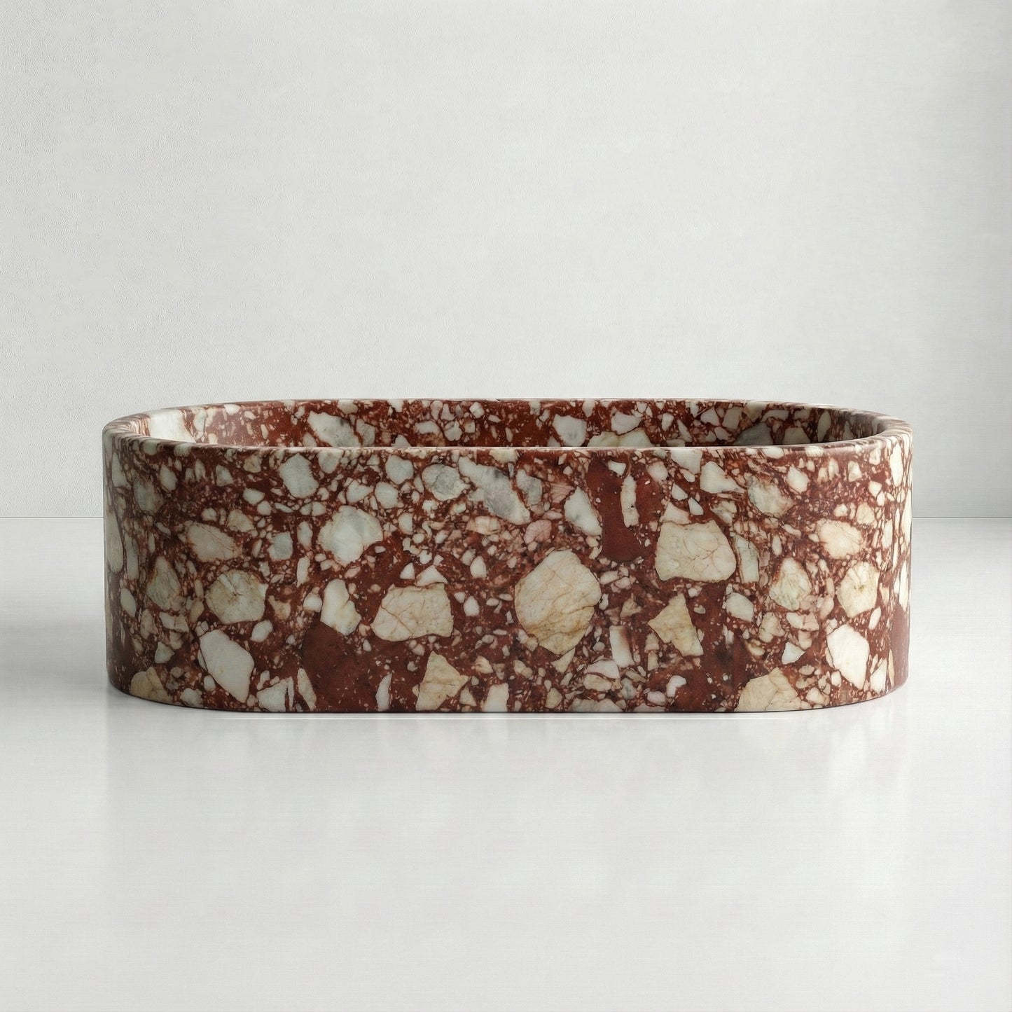 Front elevation of a solid Red Bulgari marble bathtub displaying a vibrant mosaic of deep red and white mineral fragments.