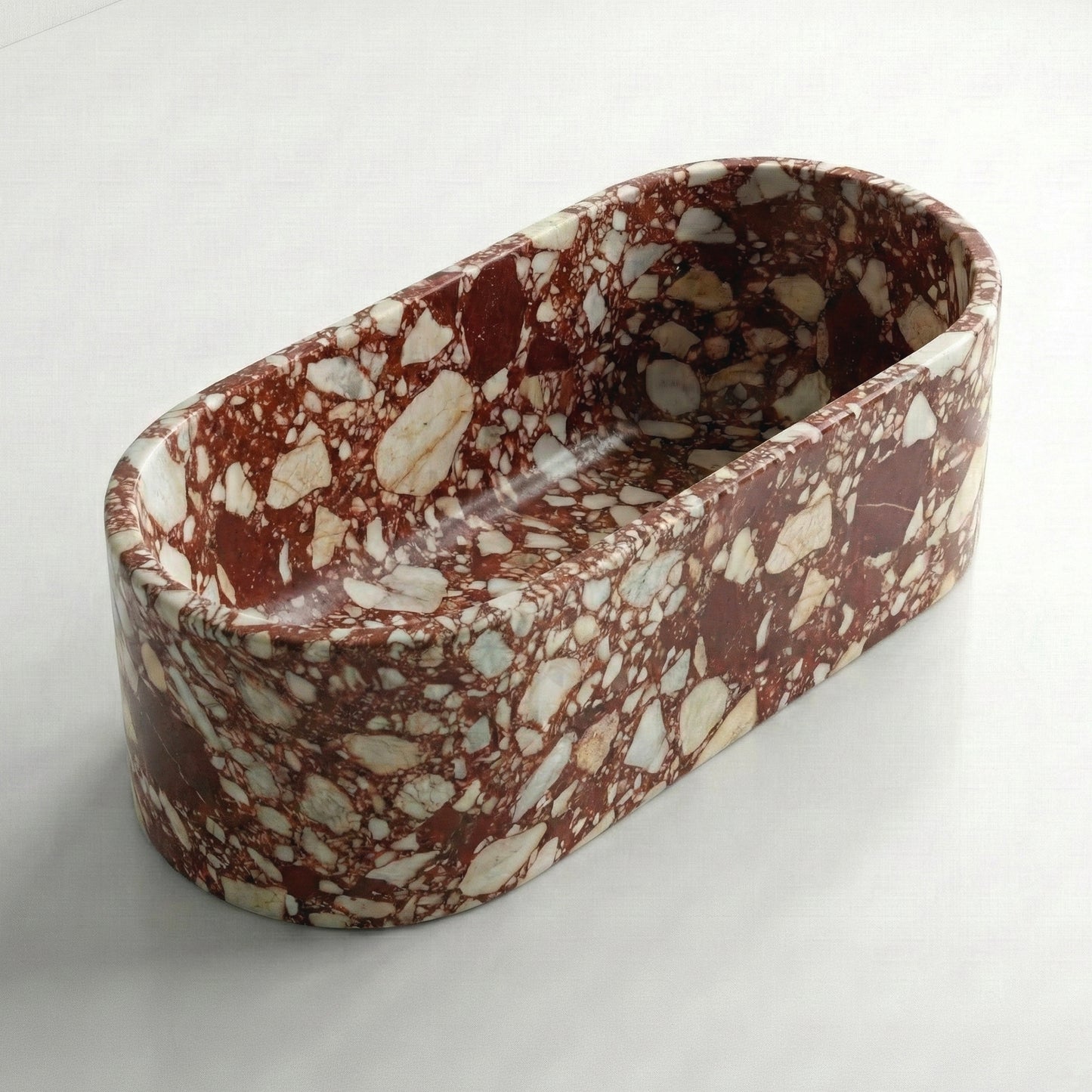 Isometric side view of a freestanding Red Bulgari marble bathtub, showcasing the bold red and white terrazzo-style natural stone pattern.
