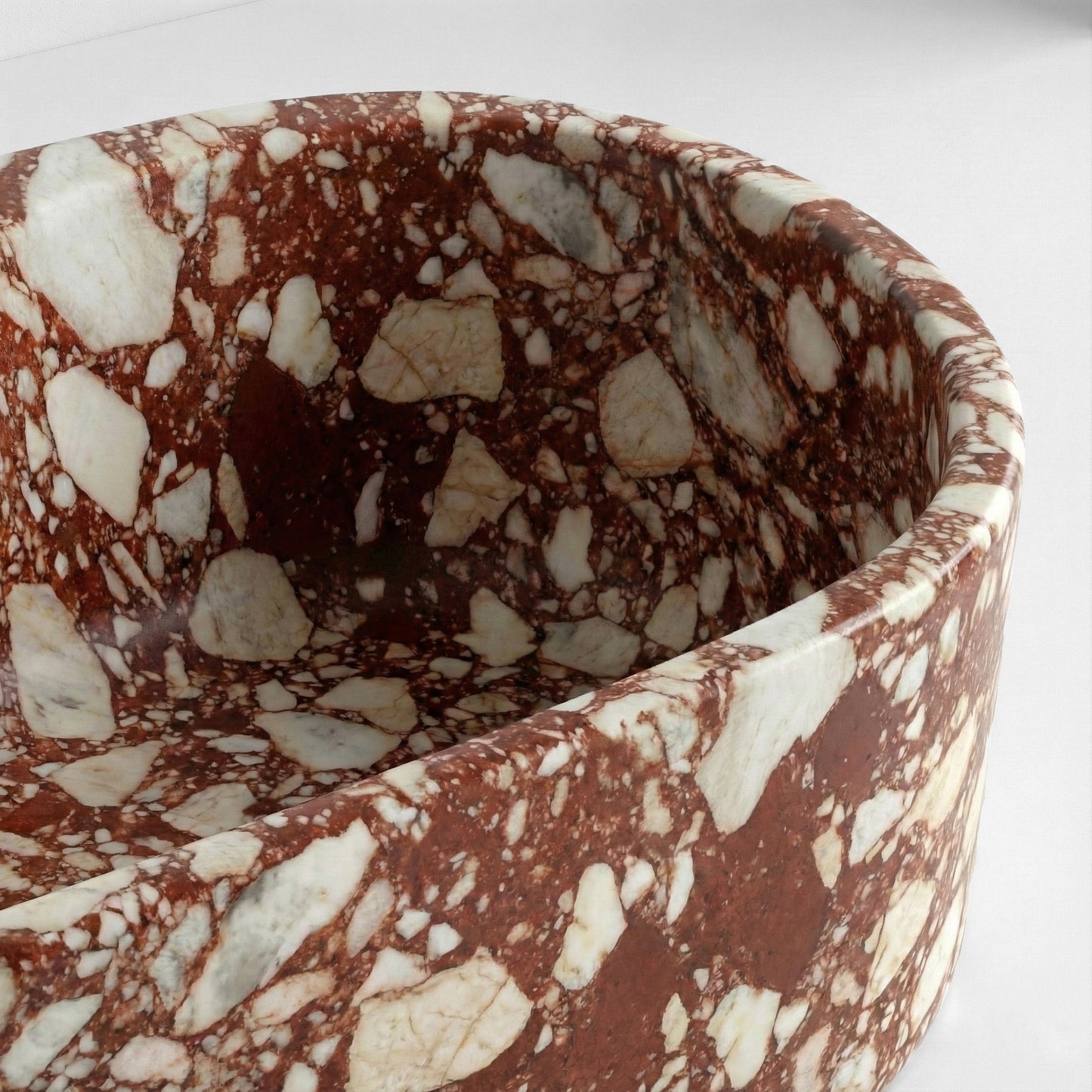 Close-up detail of a Red Bulgari marble bathtub rim featuring deep terracotta red stone with large, dramatic white brecciated clasts.