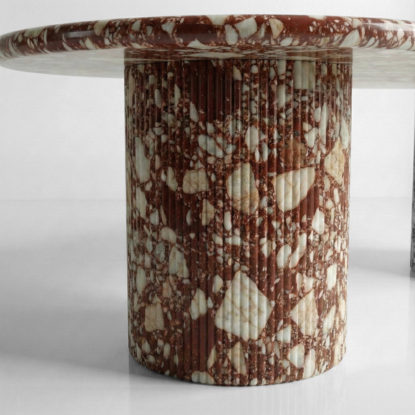 Close-up detail of a fluted column table base crafted from Red Bulgari marble, highlighting the vertical ribbed texture and complex multicolored stone composition.