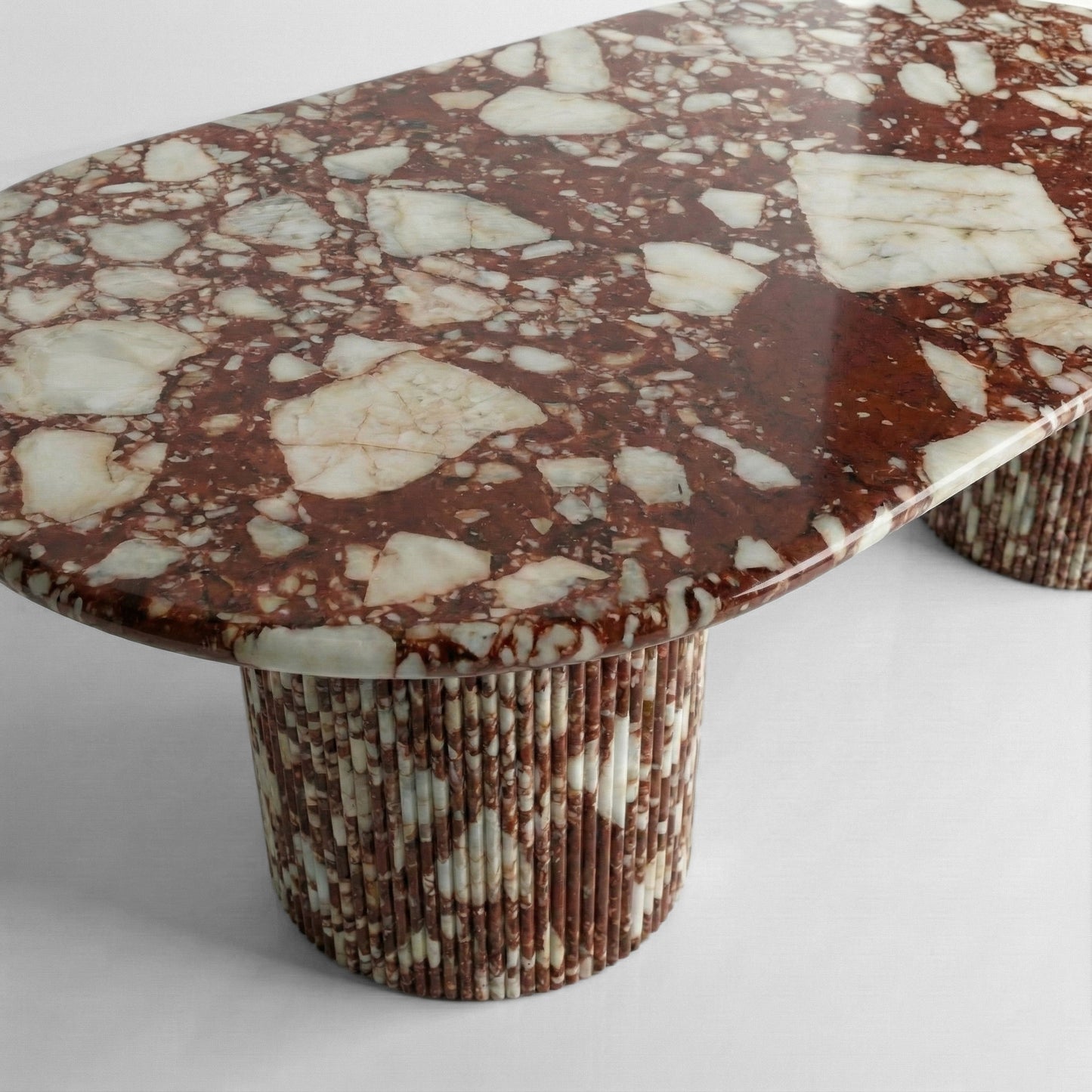 Side profile of a luxury Red Bulgari stone dining table showing the polished edge thickness and the rich contrast of deep red and white mineral chunks.
