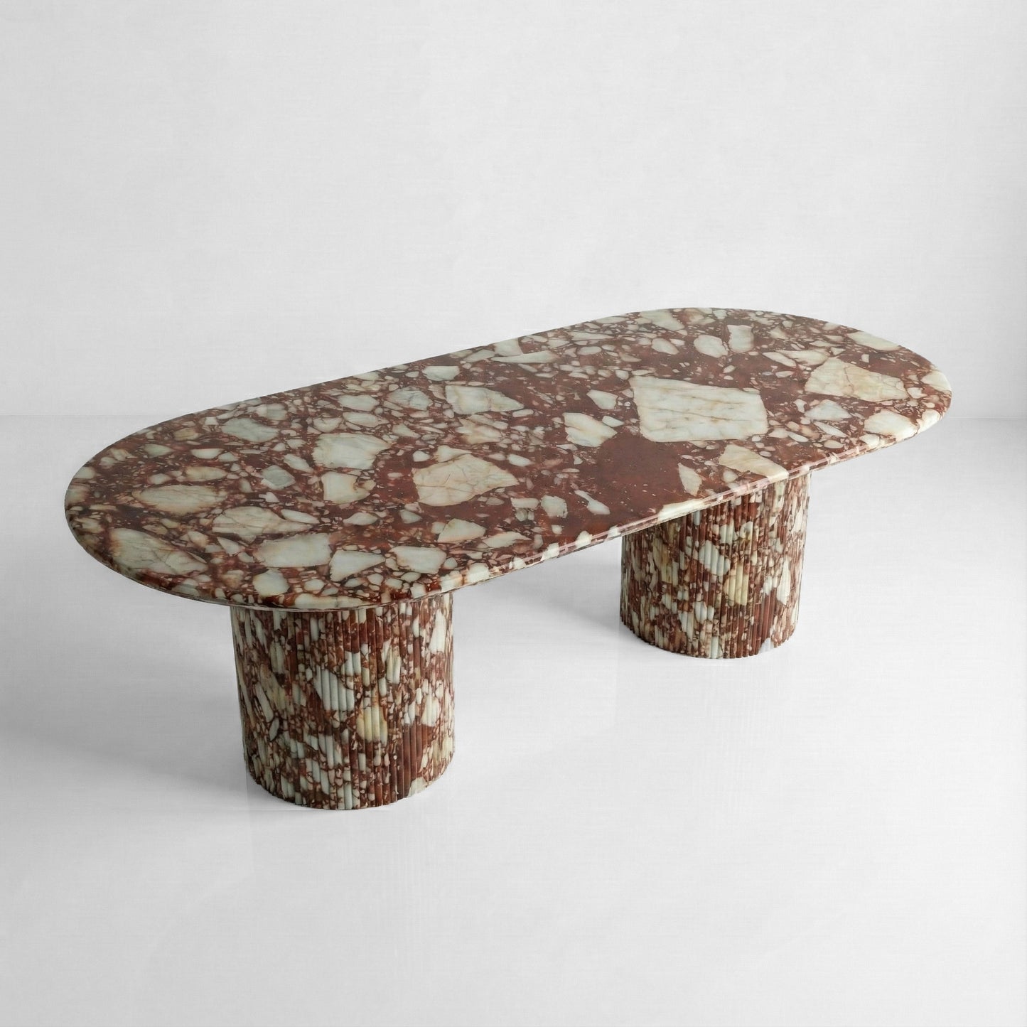 High-angle view of a statement Red Bulgari marble dining table featuring a large oval top and bold, mosaic-like burgundy and white brecciated patterns.