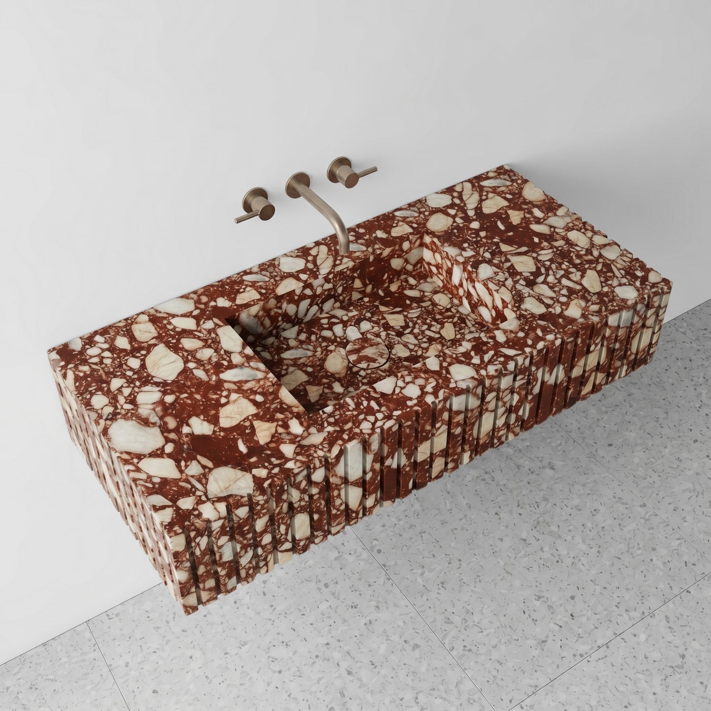 High-angle perspective view of a floating Red Bulgari marble single vanity, showcasing the dense cluster of natural cream fragments, an integrated square basin with a matching marble drain cover, and terrazzo flooring.