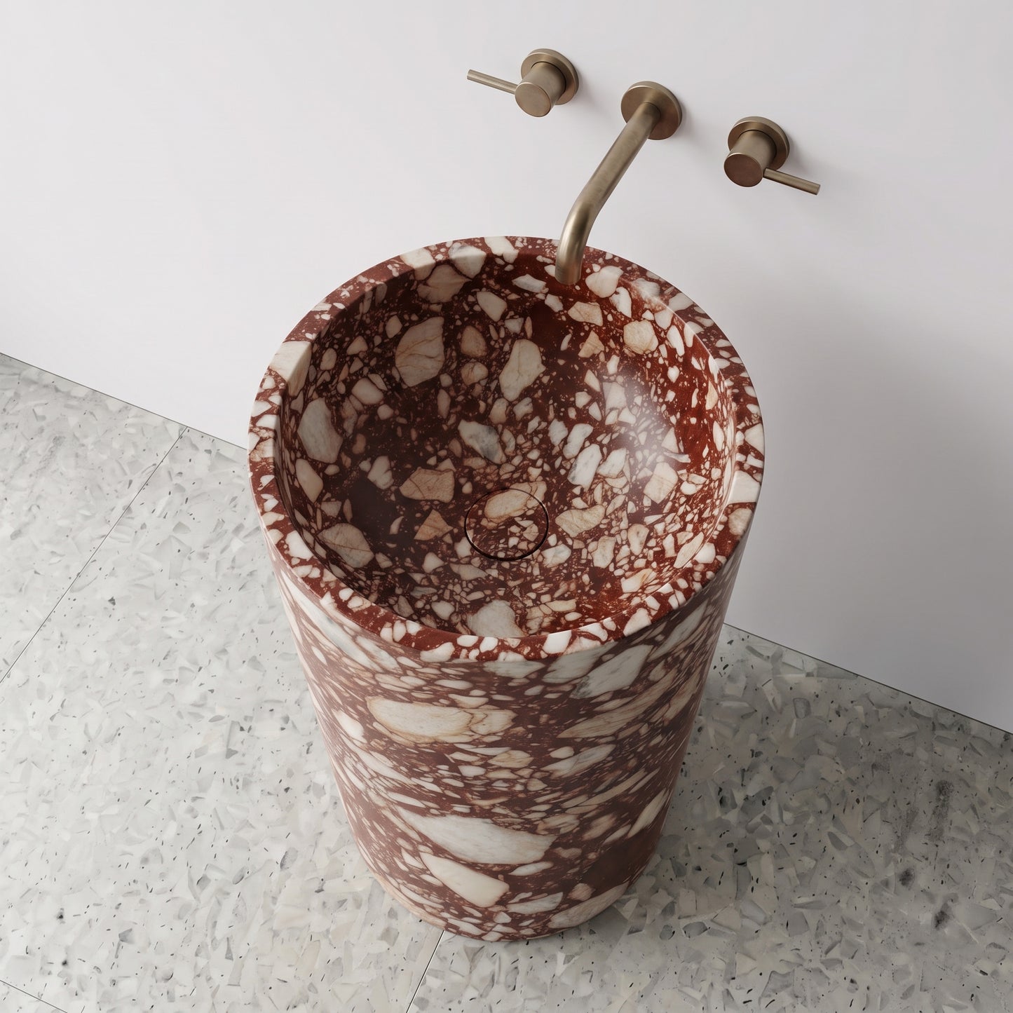 High-angle top view of a Red Bulgari cylindrical marble pedestal sink highlighting rich wine-red clasts and matching integrated stone drain cap.