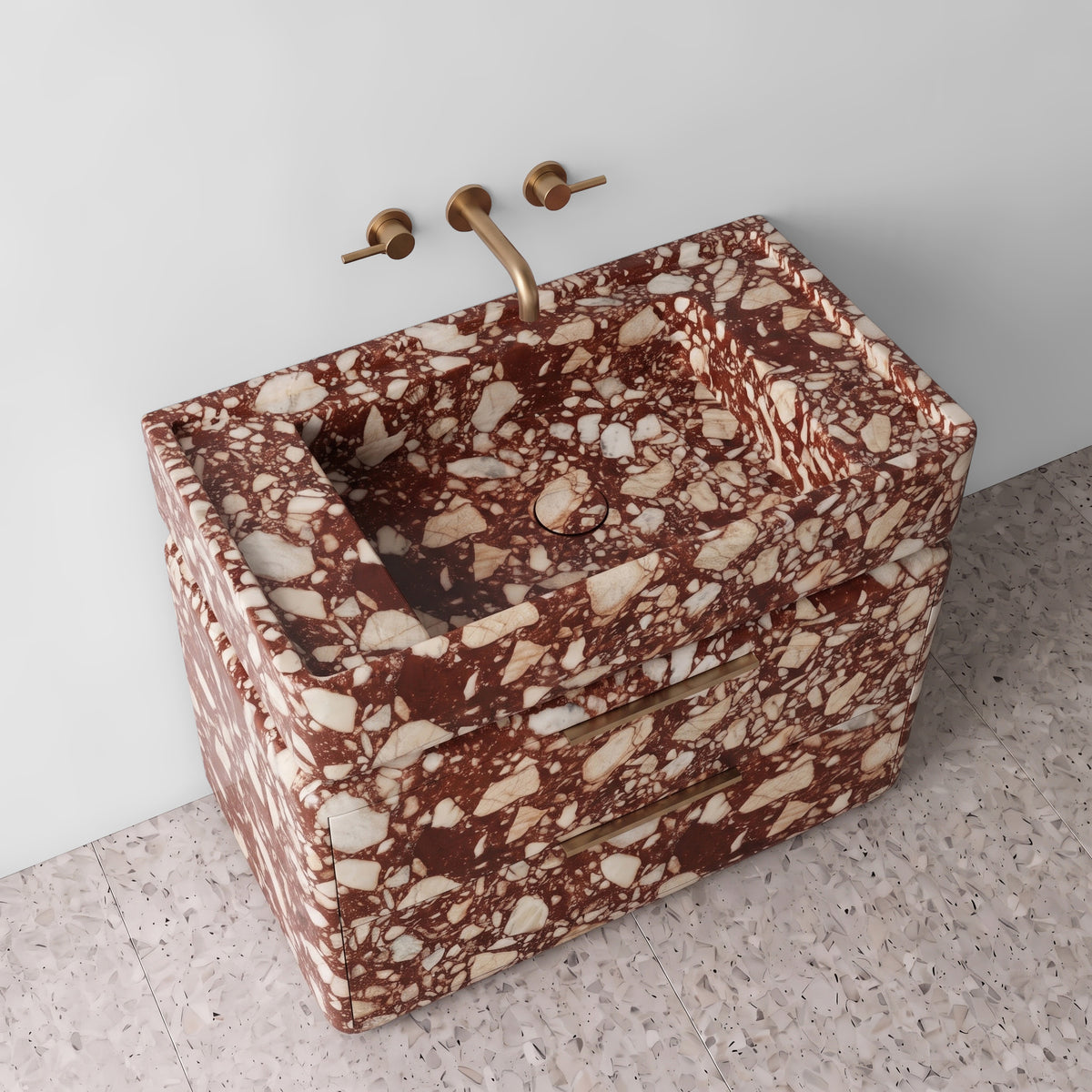 High-angle perspective view of the Red Bulgari marble double-drawer vanity, highlighting the integrated trough sink with a matching stone drain cover, raised perimeter border, rounded drawer corners, brushed brass linear hardware, and rich terracotta-red breccia stone pattern.