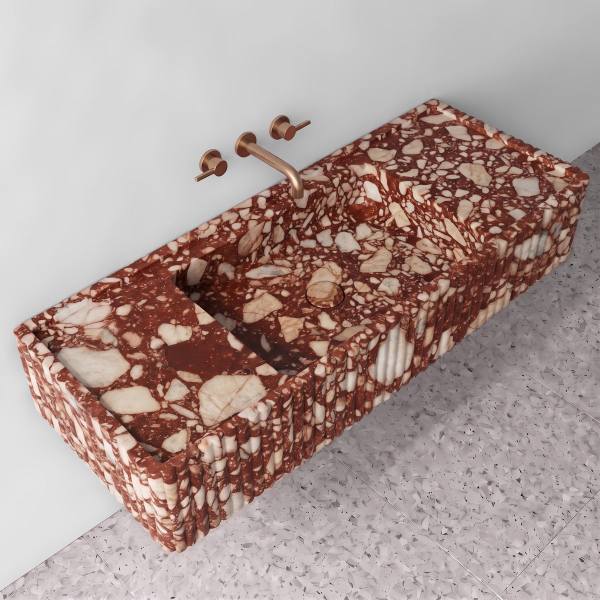 Elevated three-quarter angle of the Red Bulgari fluted monolith sink showing the integrated trough basin, matching stone drain cover, raised perimeter edge, and ribbed side detailing.